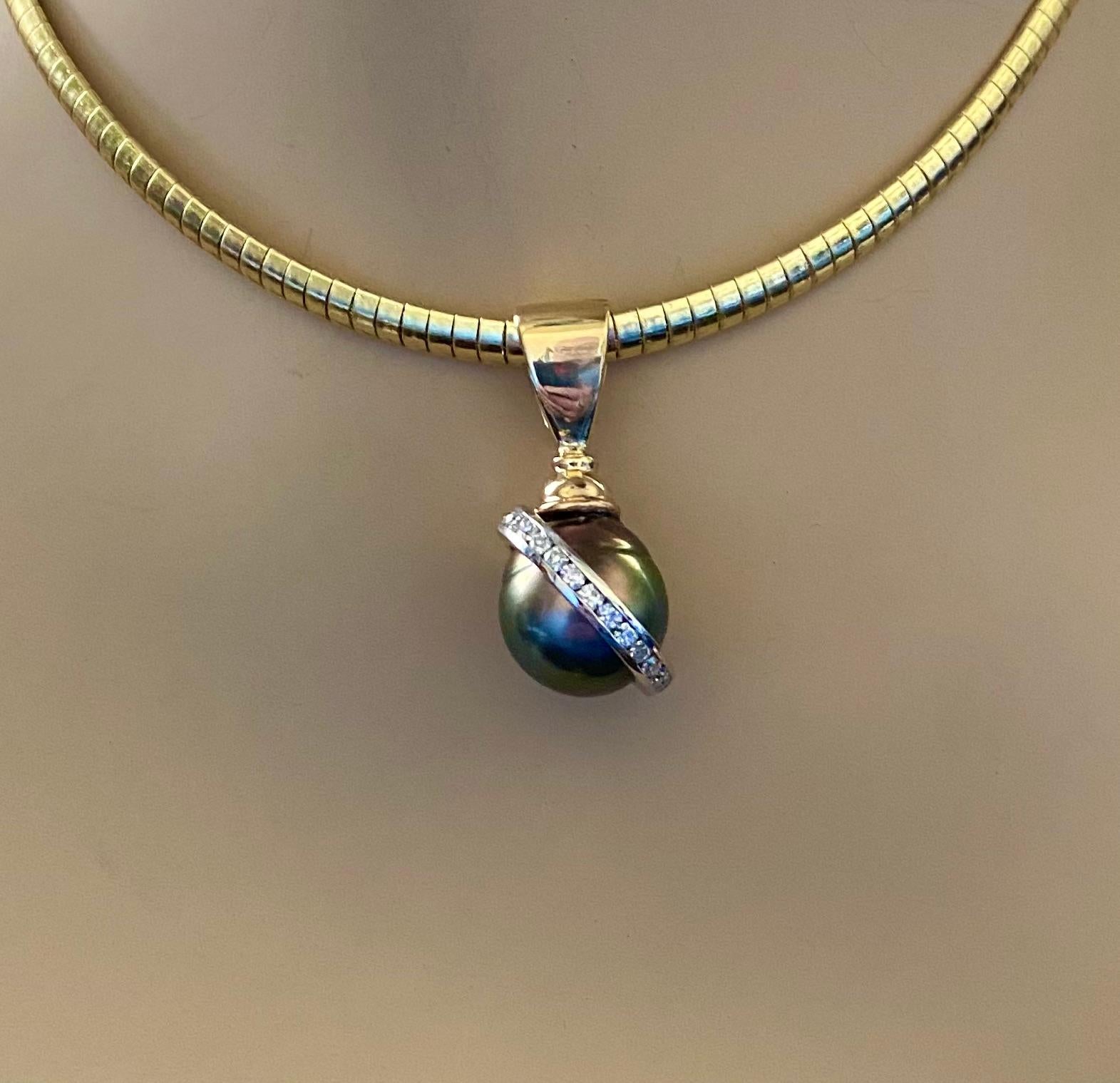 Diamonds compliment a baroque Tahitian pearl in this Saturn pendant.  The pearl measures 14.4mm, is medium gray in color and possesses excellent luster.  Swirling around the pearl are channel set diamonds  in white gold.  The mounting is 18k yellow