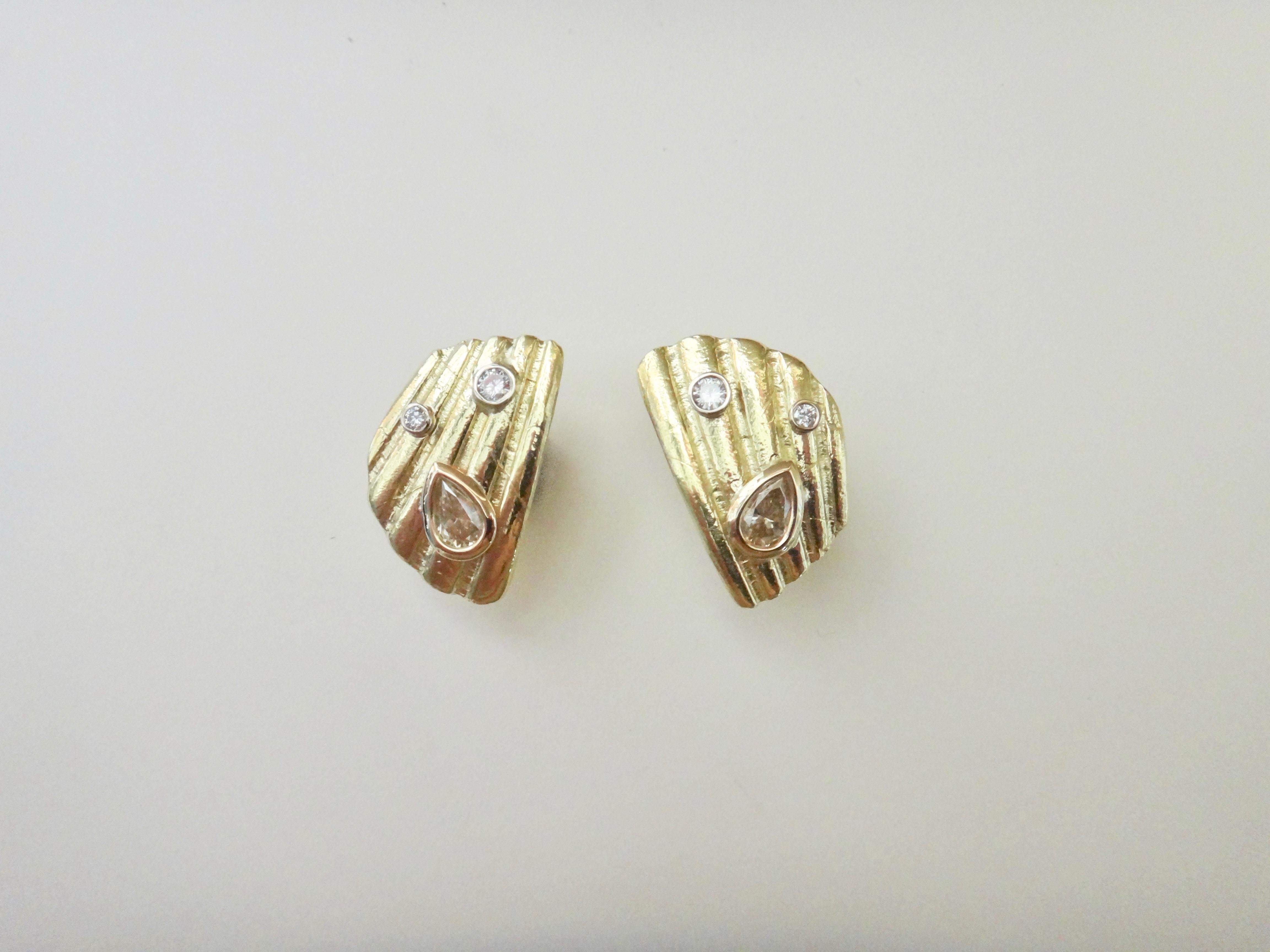 A fragment from an actual shell, tumble polished on the beach was molded to create these 18k yellow gold earrings.  Decorating the surface of each earring are three diamonds.  Two white brilliant cut diamonds are bezel set along with a pear shaped