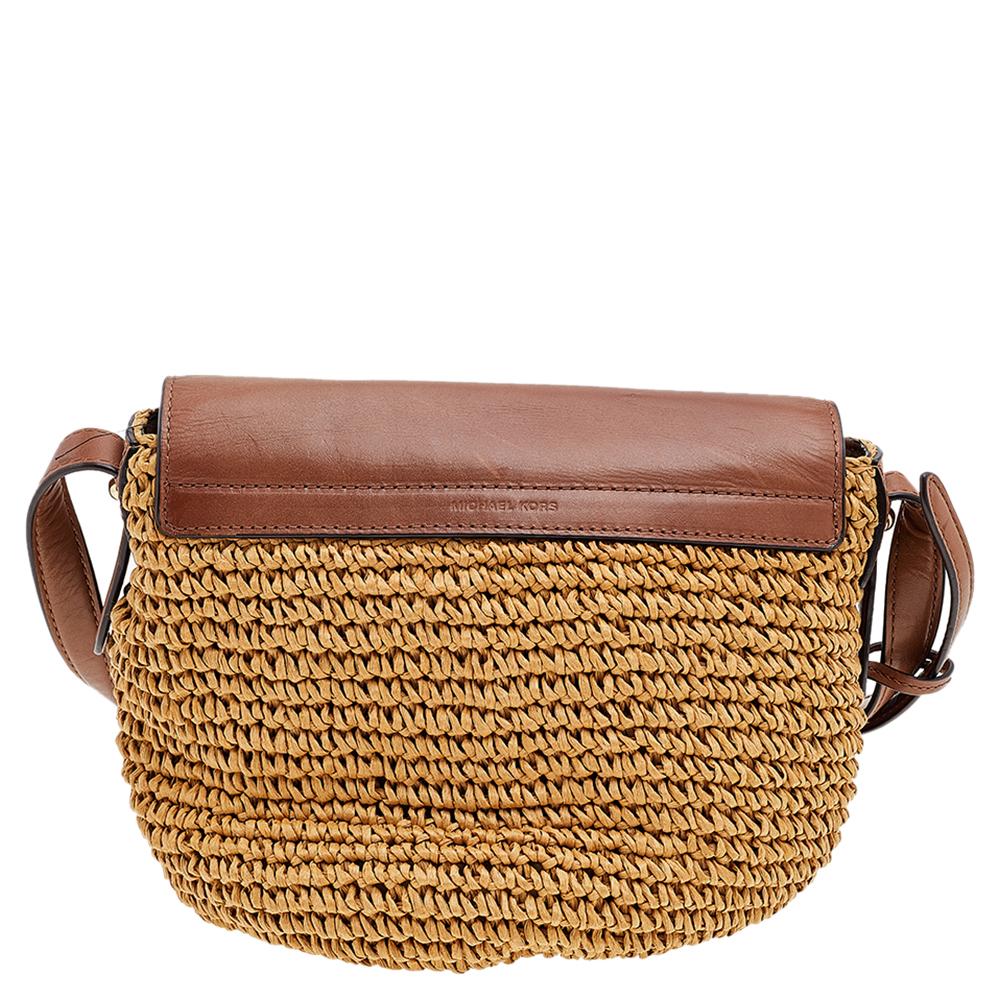 Zeigen Sie einen erstaunlichen Stil mit dieser wunderbaren Tasche von Michael Kors. Die Außenseite dieser Tasche besteht aus beigefarbenem gewebtem Stroh und braunem Leder mit einem goldfarbenen Schnallenverschluss an der Vorderseite. Sie wird von