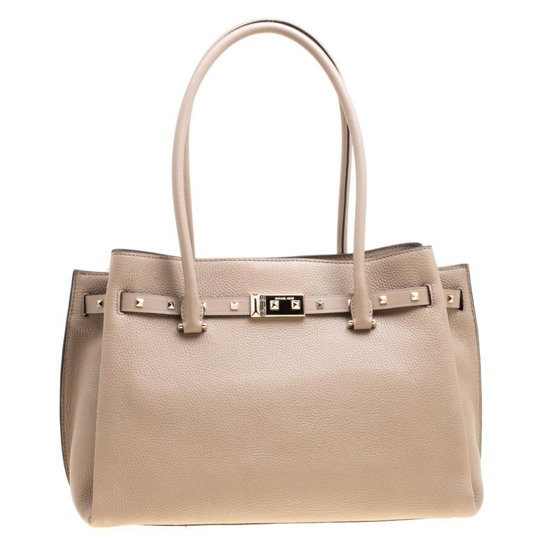 Crafted from a beige pebbled leather body, this Addison tote is perfect for everyday. Set on protective base studs, this bag comes fitted with two rolled top handles and the signature brand lettering on the top exterior. This bag features a studded