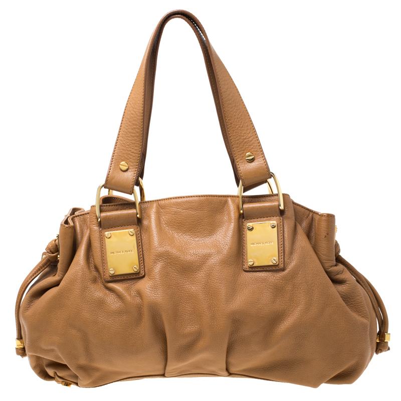 This Michael Kors satchel is a fashion ally that never fails to increase your style quotient. Crafted from brown leather the bag features dual handles and gold-tone hardware. The satin-lined interior houses a zip pocket and slip pockets.

Includes: