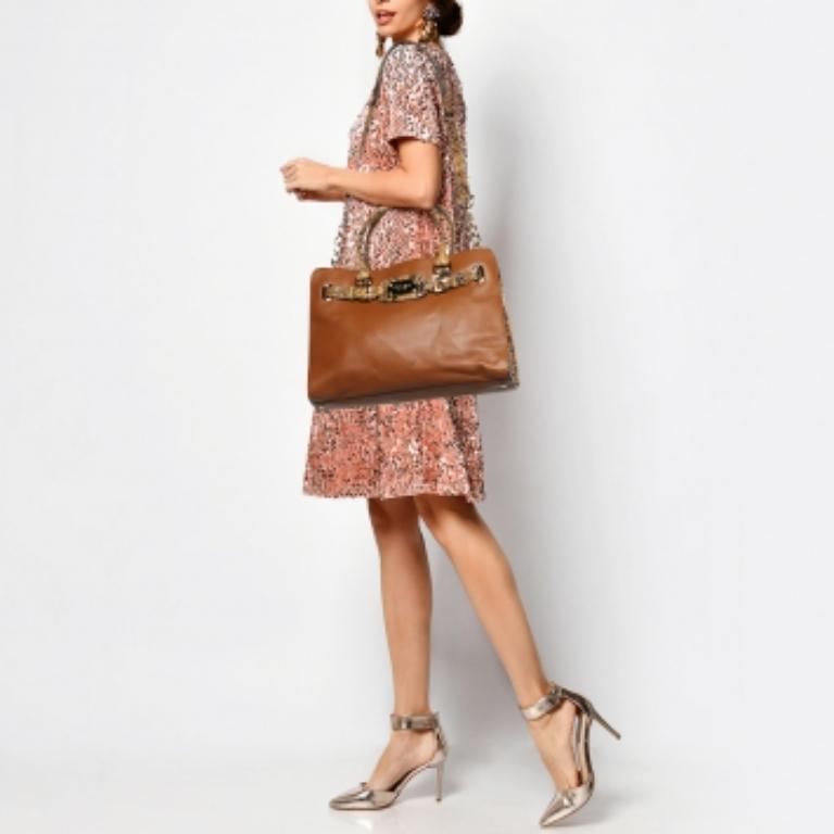 Las asas dobles y la correa para el hombro hacen que este bolso tote Michael Kors Hamilton sea ideal para el día a día. Fabricada en piel de serpiente repujada, está adornada con detalles dorados e incorpora una placa de la marca en la solapa