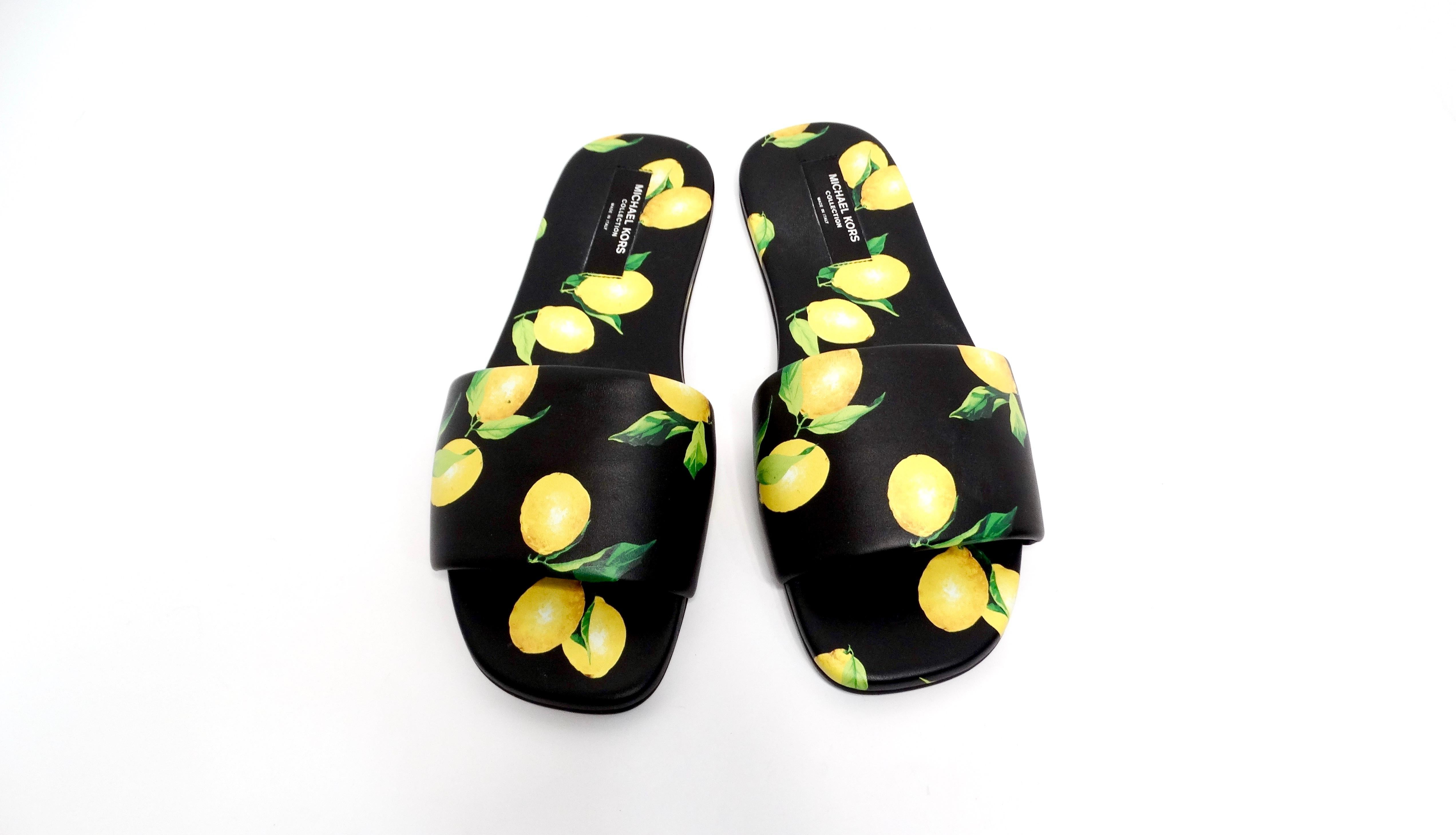 Introducing the Michael Kors Collection Lemon Print Leather Delphine Slides, a vibrant and playful addition to your footwear collection. These chic slip-on slides feature a striking black leather base adorned with a whimsical print of yellow lemons