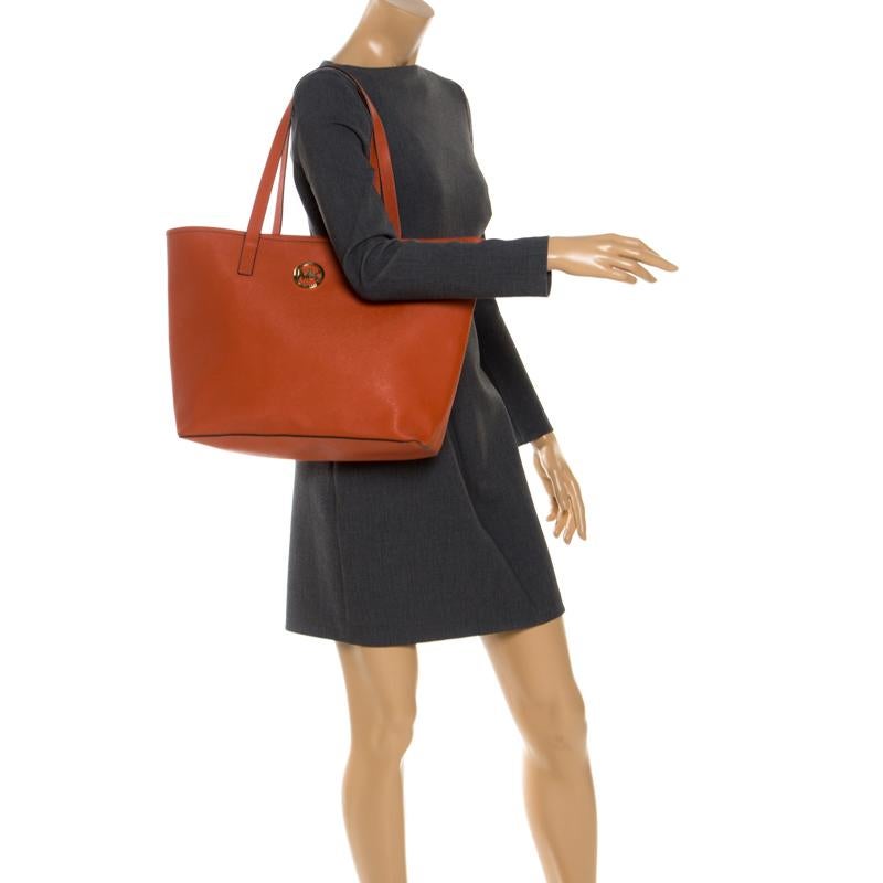 This shopper tote from Michael Kors is a fabulous piece. The bag comes in a luxurious orange exterior made from leather and accented with the brand logo on the front. It features dual handles and a nylon-lined interior perfectly sized to easily hold
