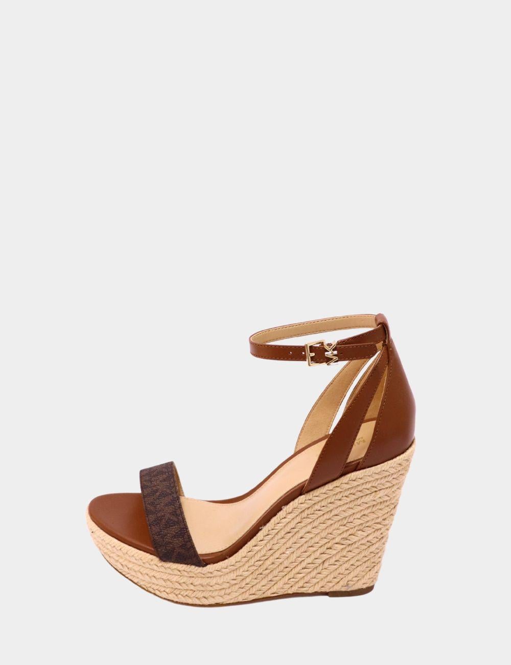 Entra in uno stile pronto per l'estate con questi sandali con zeppa di Michael Kors, progettati per una versatilità chic. Caratterizzati da un cinturino in pelle marrone e tessuto con logo, questi sandali offrono una classica silhouette open-toe con