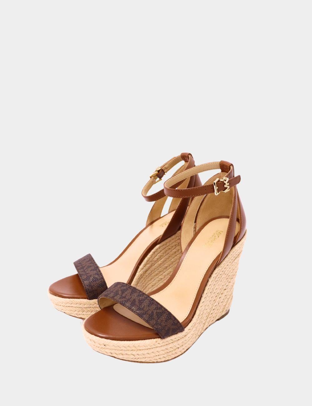 Michael Kors Sandali con zeppa in pelle marrone e logo in rafia - Tacchi con plateau alla caviglia


Entra nella raffinatezza estiva con questi sandali con zeppa in rafia di Michael Kors. Progettati con un mix di pelle marrone liscia e tela firmata