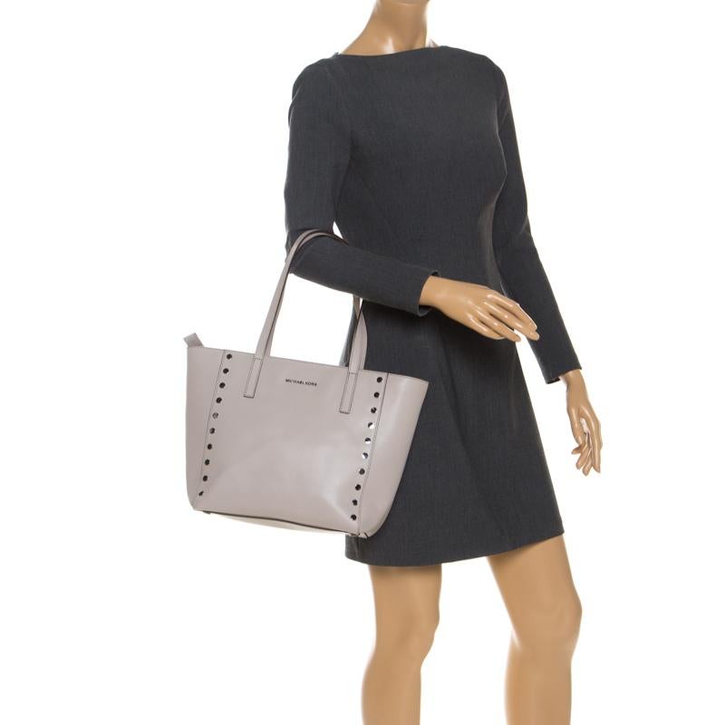 This Rivington bag from Michael Kors has been crafted from durable leather in a simple shape. It comes fitted with two slender top handles and detailed with silver-tone studs along the edges. Secured with a top zipper, this functional bag can easily