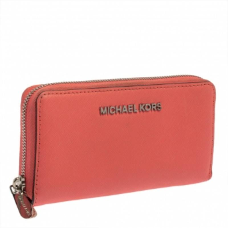 This wristlet wallet by Michael Kors makes for a great accessory. It is crafted from pink leather, features a zip closure that opens to a fabric and leather interior that can hold all your essentials in an organized manner. It is finished with
