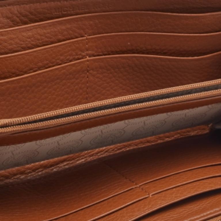 Ce superbe portefeuille de Michael Kors est un objet de mode à posséder absolument. Il est réalisé en cuir fauve et comporte une plaque de logo dorée sur le devant. Il est doté d'une fermeture à glissière qui permet d'accéder à un intérieur bien