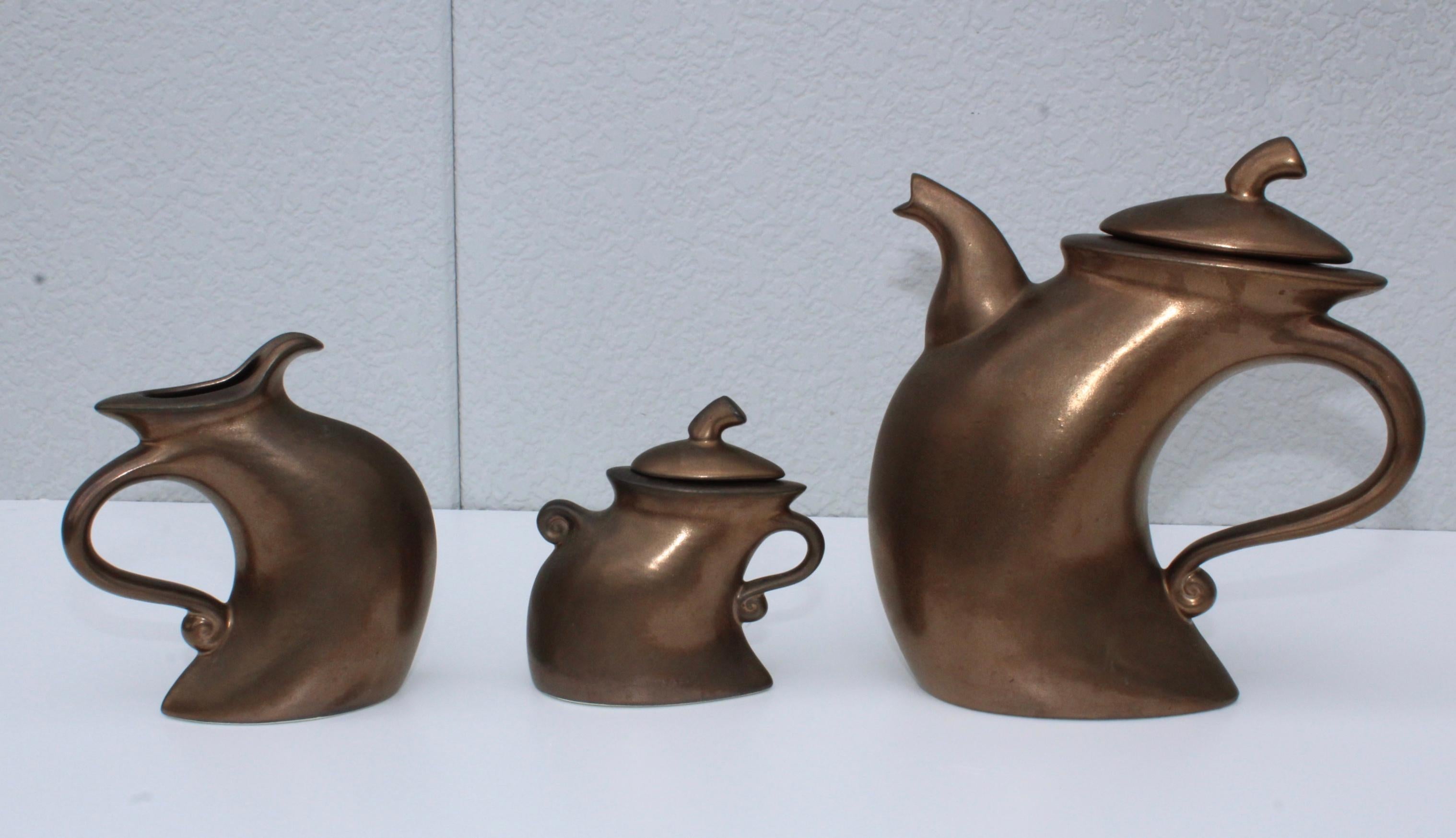 1980's modernist tea set by California ceramist Michael Lambert, in vintage original condition with minor wear and patina due to age and use.

Sugar holder measurements: height 5.5'' depth 2.75'' width 6''
Creamer height 7'' width 7'' depth 3''.