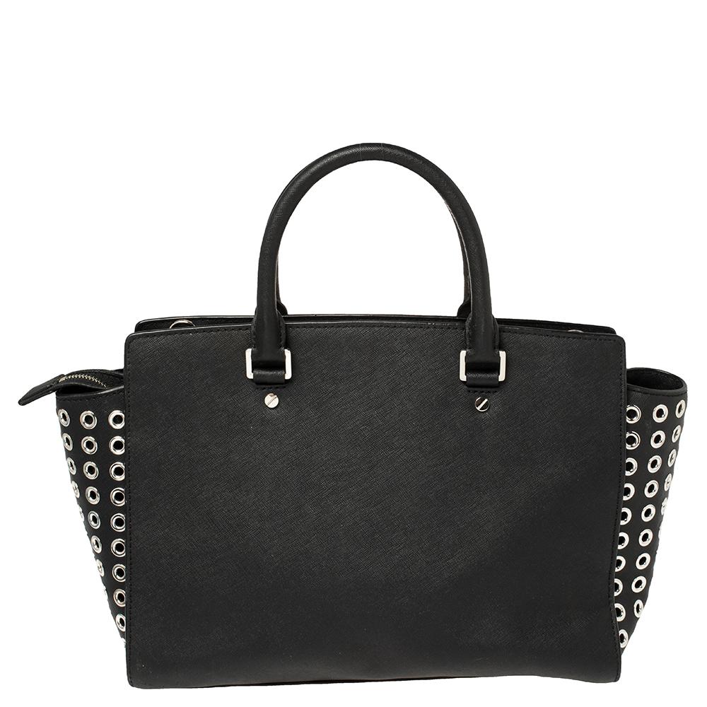 Diese bezaubernde Selma-Tasche von Michael Michael Kors ist sowohl elegant als auch modisch. Die aus schwarzem Leder gefertigte Tasche verfügt über einen abnehmbaren Schulterriemen und zwei obere Griffe. Das nylongefütterte Innere beherbergt eine