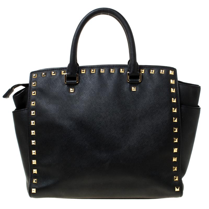 Elevate your style with this gorgeous Selma tote by Michael Michael Kors. Crafted from black leather, the bag is enhanced with studs. It features dual top handles, detachable shoulder strap and protective metal feet at the bottom. It has a spacious