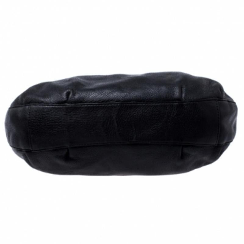 Questa borsa della maison Michael Kors è un modello da portare sempre con sé, stagione dopo stagione. È stata realizzata con un corpo in pelle nera e presenta ritagli sulla parte superiore. È dotata di due manici superiori intrecciati e di charm con