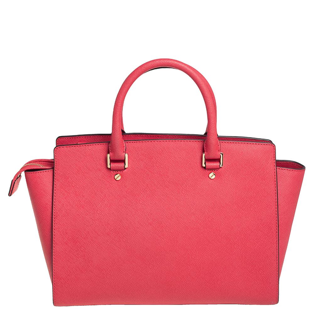 Diese bezaubernde Selma-Tasche von MICHAEL Michael Kors ist elegant und modisch zugleich. Die Tasche ist aus korallenrosa Saffiano-Leder gefertigt und hat zwei Griffe an der Oberseite. Das nylongefütterte Innere beherbergt eine Reißverschlusstasche
