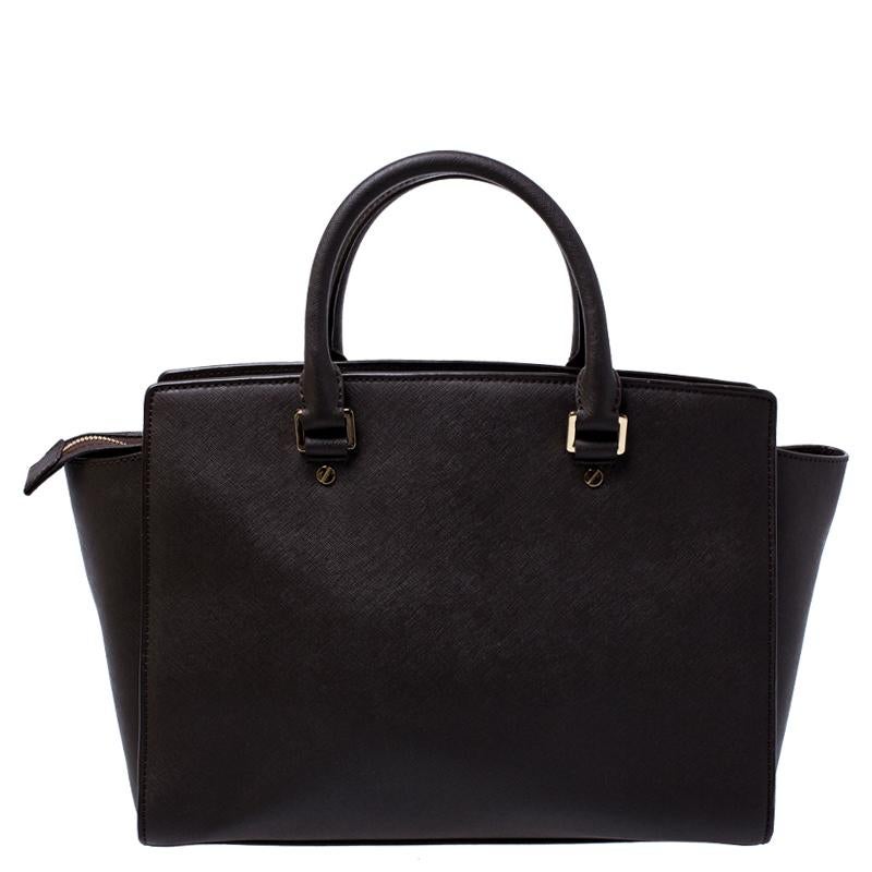 Carry this gorgeous Selma tote by Michael Kors to all your outings. Crafted from Saffiano leather the bag features dual top handles and protective metal feet at the bottom. It has a spacious fabric-lined interior that will hold all your daily