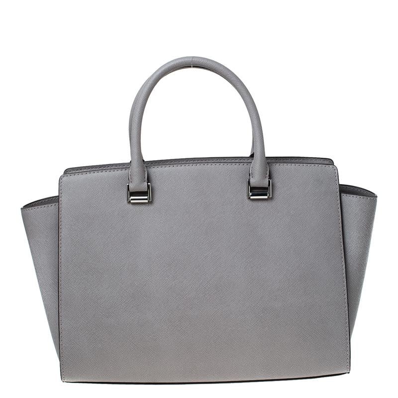 Carry this gorgeous Selma tote by Michael Kors to all your outings. Crafted from leather the bag features a detachable shoulder strap and silver-tone hardware. It has a spacious fabric-lined interior that will hold all your daily necessities. This