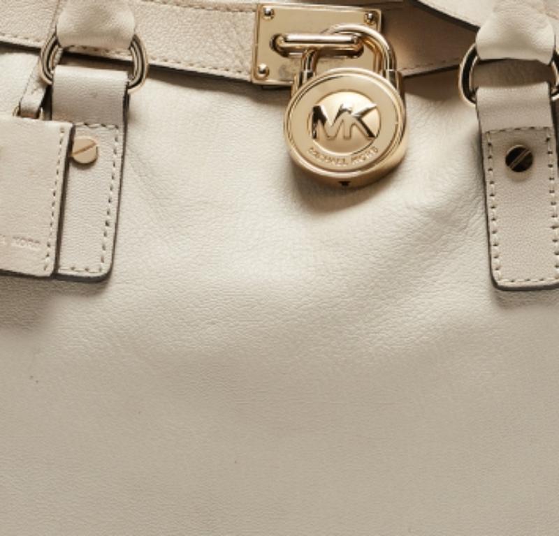 Questa tote Hamilton North South è di Michael Kors. È realizzata in pelle beige chiaro e decorata con un lucchetto inciso sul davanti. La borsa ha due manici, una tracolla e uno spazioso interno in tessuto. Questa creazione è ideale per l'uso