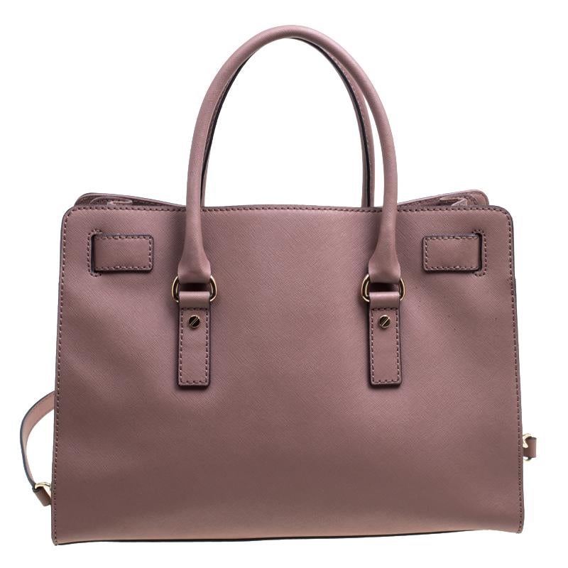 This simple Hamilton tote from Michael Kors is a worthy buy. It has been crafted from leather in a classy pale pink shade and decorated with an engraved padlock on the front. The bag has two handles, a shoulder strap, and a spacious fabric interior.