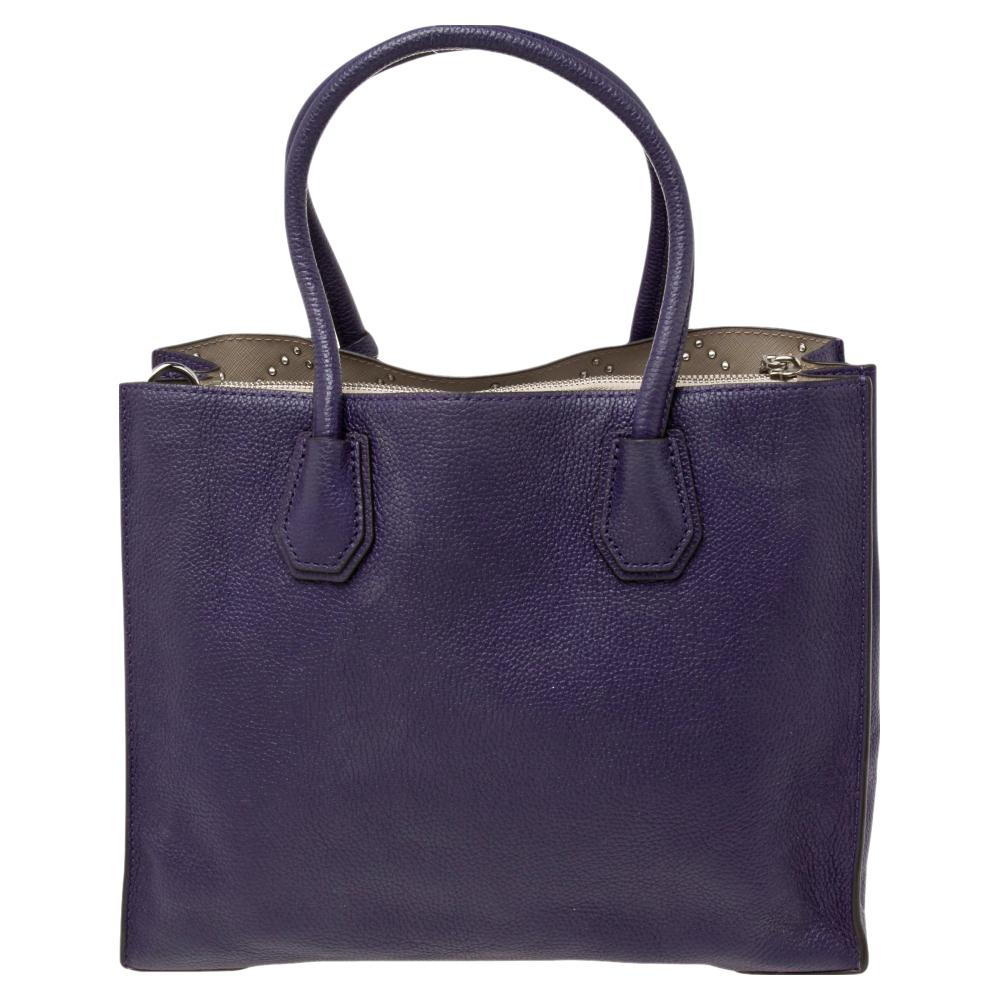 Featuring a chic and fabulous style, this MICHAEL Michael Kors tote is modern. Crafted from leather in plum, the tote features dual handles, a removable shoulder strap, and a padlock. It opens to a spacious leather & nylon interior divided by a