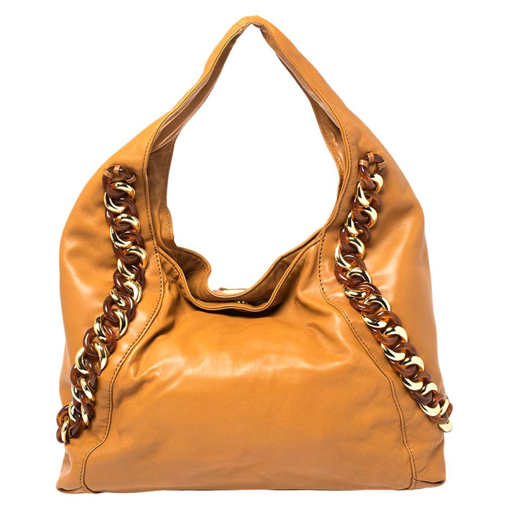 This tan leather bag is gorgeous enough to upgrade any look. It boasts gorgeous chain trims on the exterior, brand label on the front, a single handle, and a spacious canvas-lined interior. This MICHAEL Michael Kors hobo is just what you need to