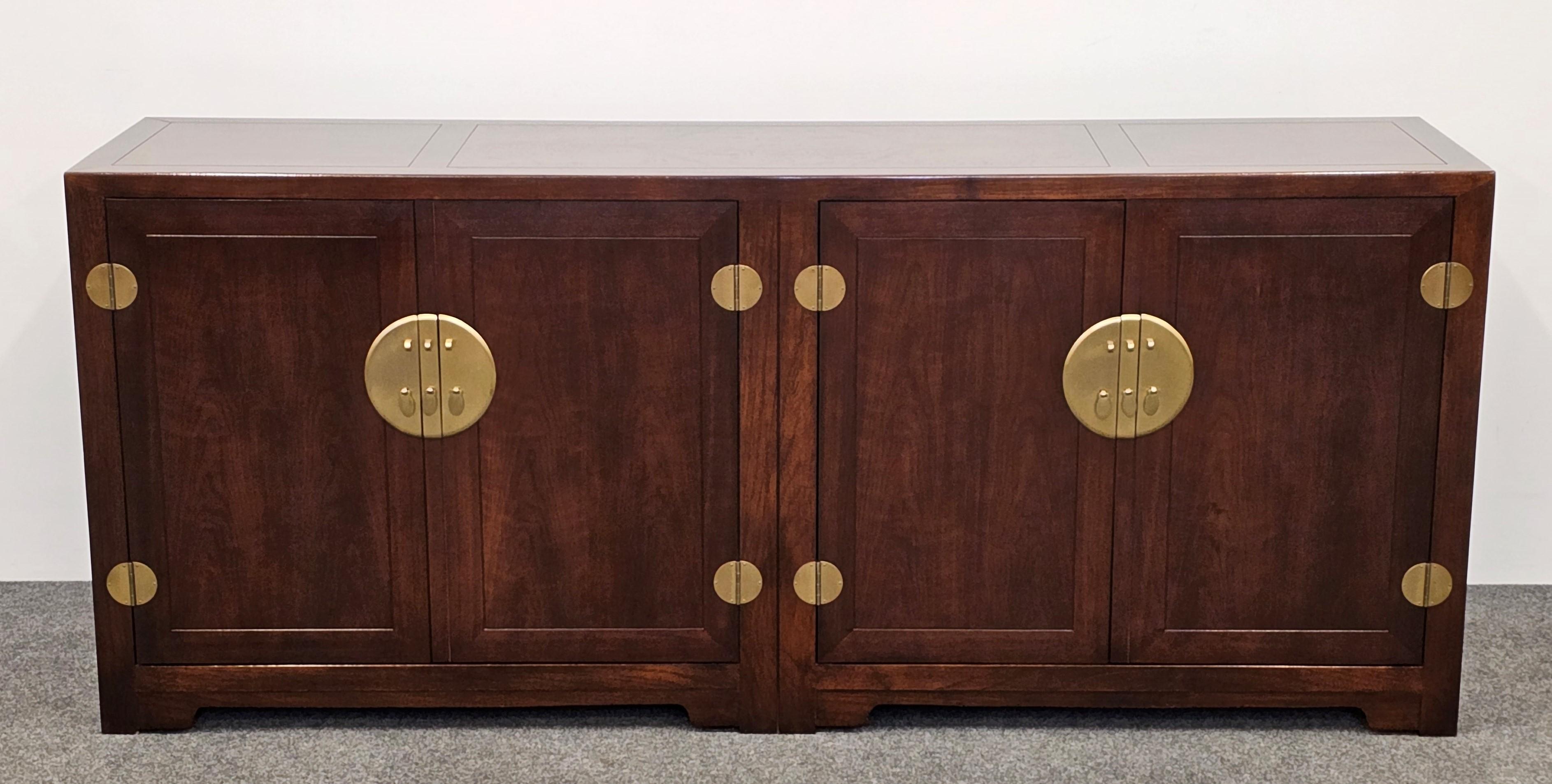 An elegant Baker Credenza or sideboard in the manner of Michael Taylor. This Asian-style cabinet has beautiful brass accents and hardware. The credenza has a warm walnut finish with a burl wood top. This stunning designer piece would work well in