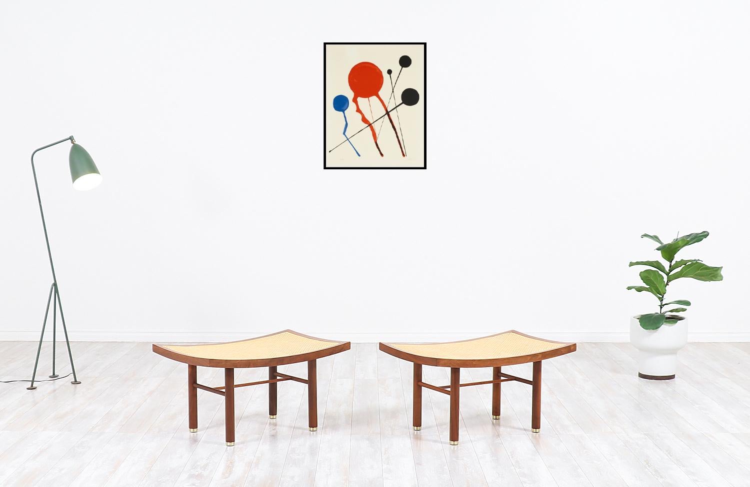 A stylish pair of cane stools designed by Michael Taylor in collaboration with Baker Furniture Co. in the United States, circa 1950s. These iconic and elegant stools feature a solid walnut construction with polished brass sabots and new caning for