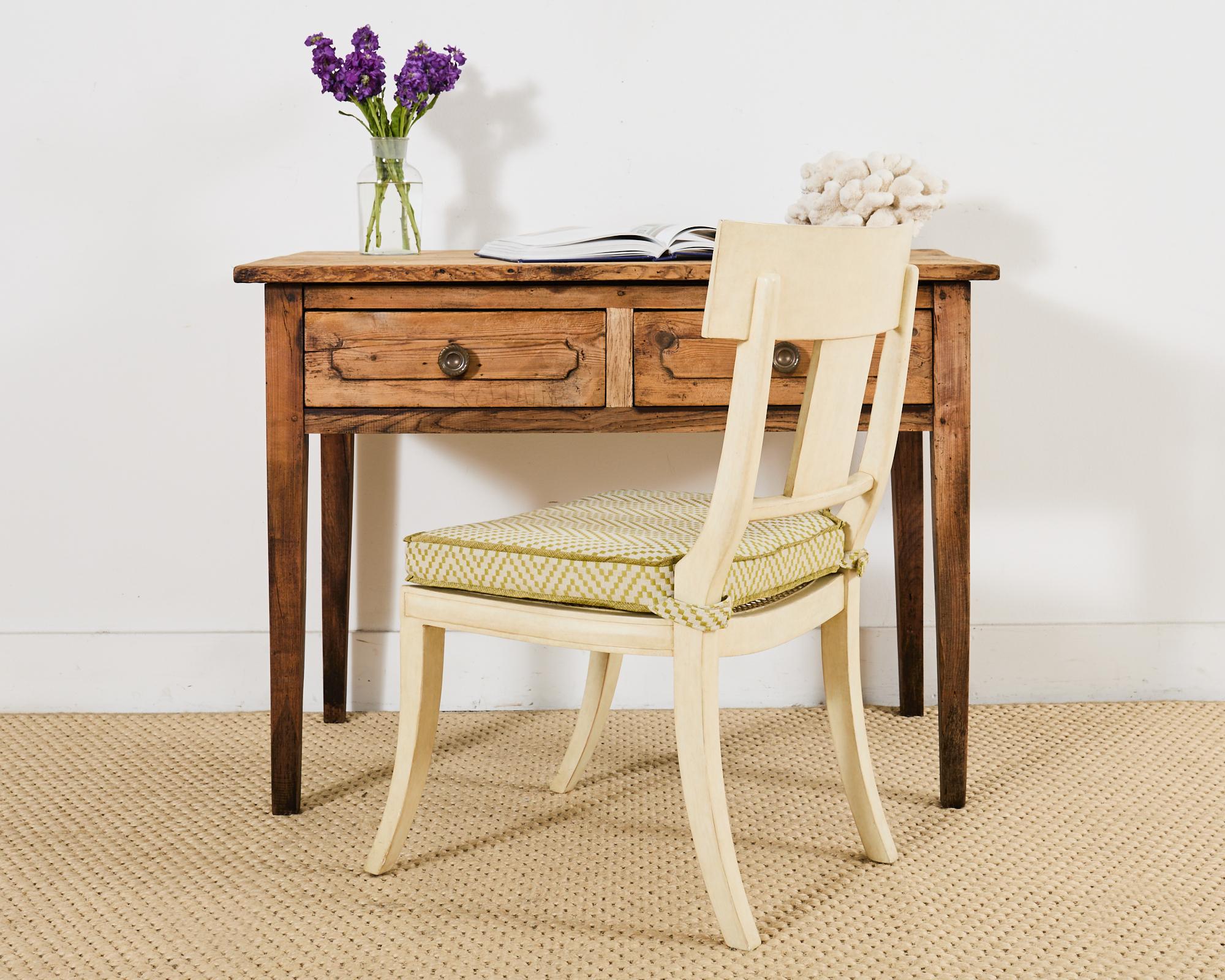 Iconic Michael Taylor design white dining chair featuring a cream lacquered finish. Designed in the neoclassical taste with a greco-roman klismos chair inspiration. The seat has a tablet shaped back and a generous seat inset with woven cane. The