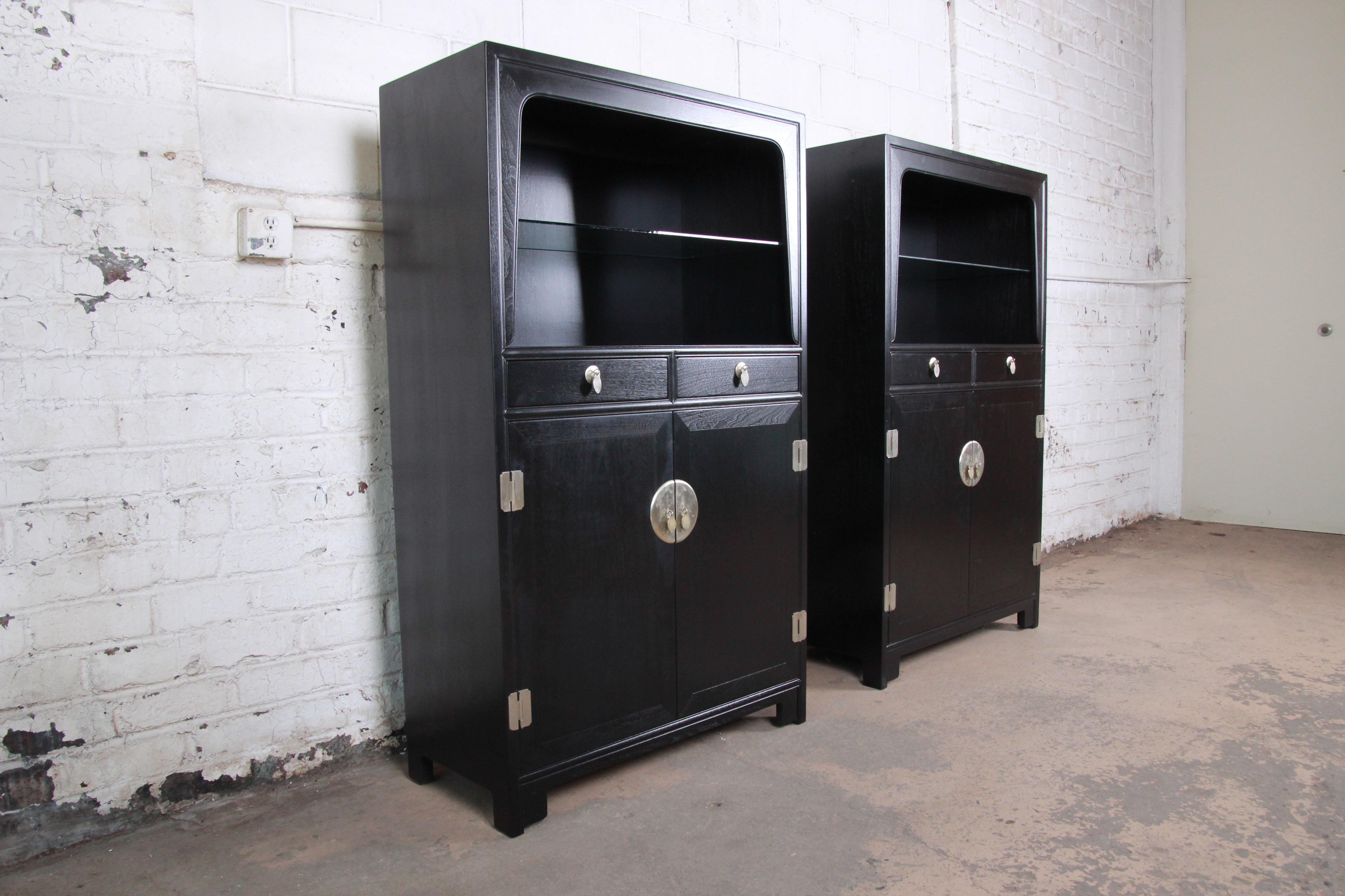An exceptional pair of chinoiserie wall units or display cabinets from the Far East Collection by Michael Taylor for Baker Furniture. The cabinets feature beautiful walnut wood grain with a newly ebonized finish. They have a simple midcentury