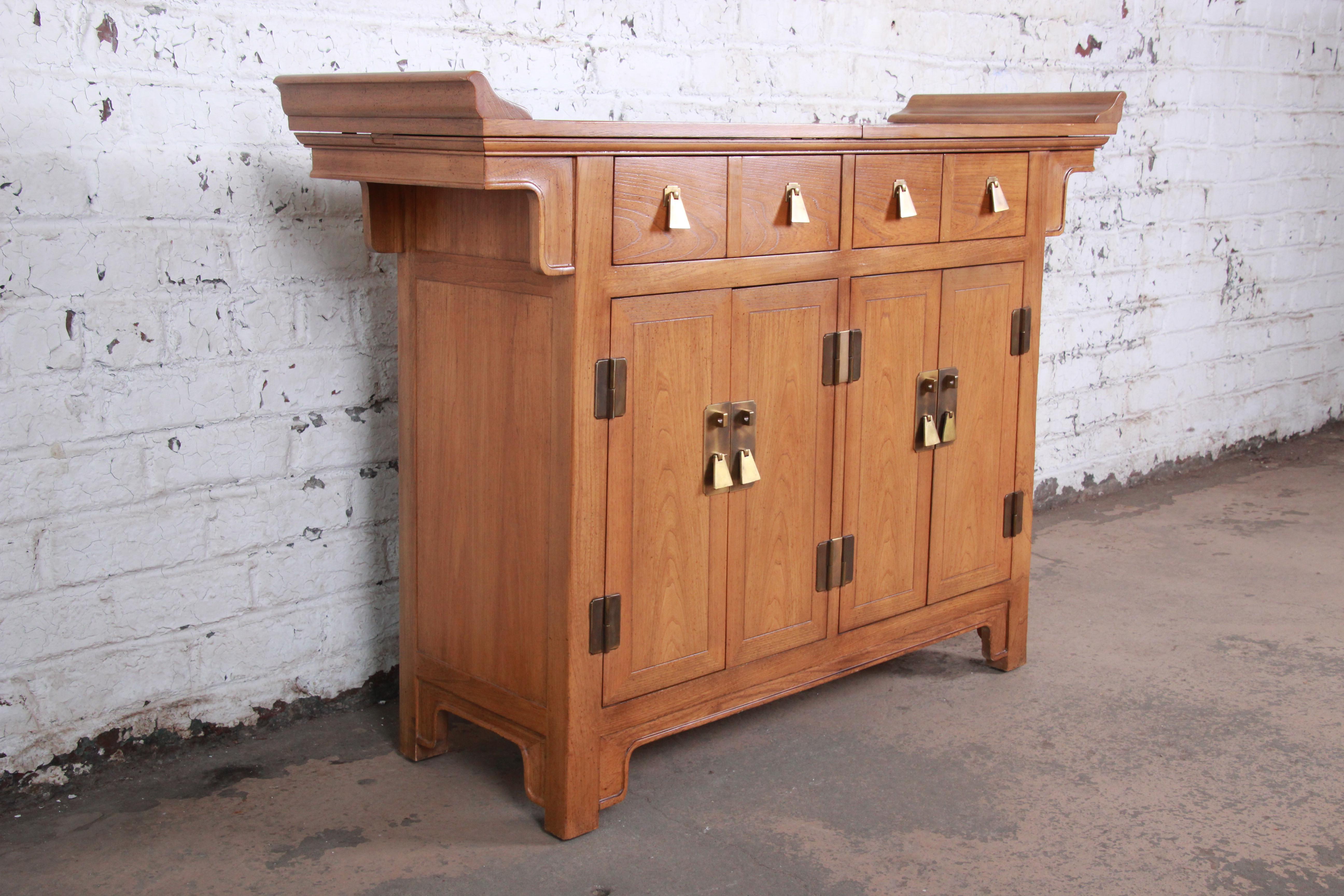A gorgeous mid-century Hollywood Regency chinoiserie buffet server or bar cabinet by Michael Taylor for Baker furniture. The server features beautiful wood grain with solid elm wood construction and a nice Asian design. It offers excellent storage,