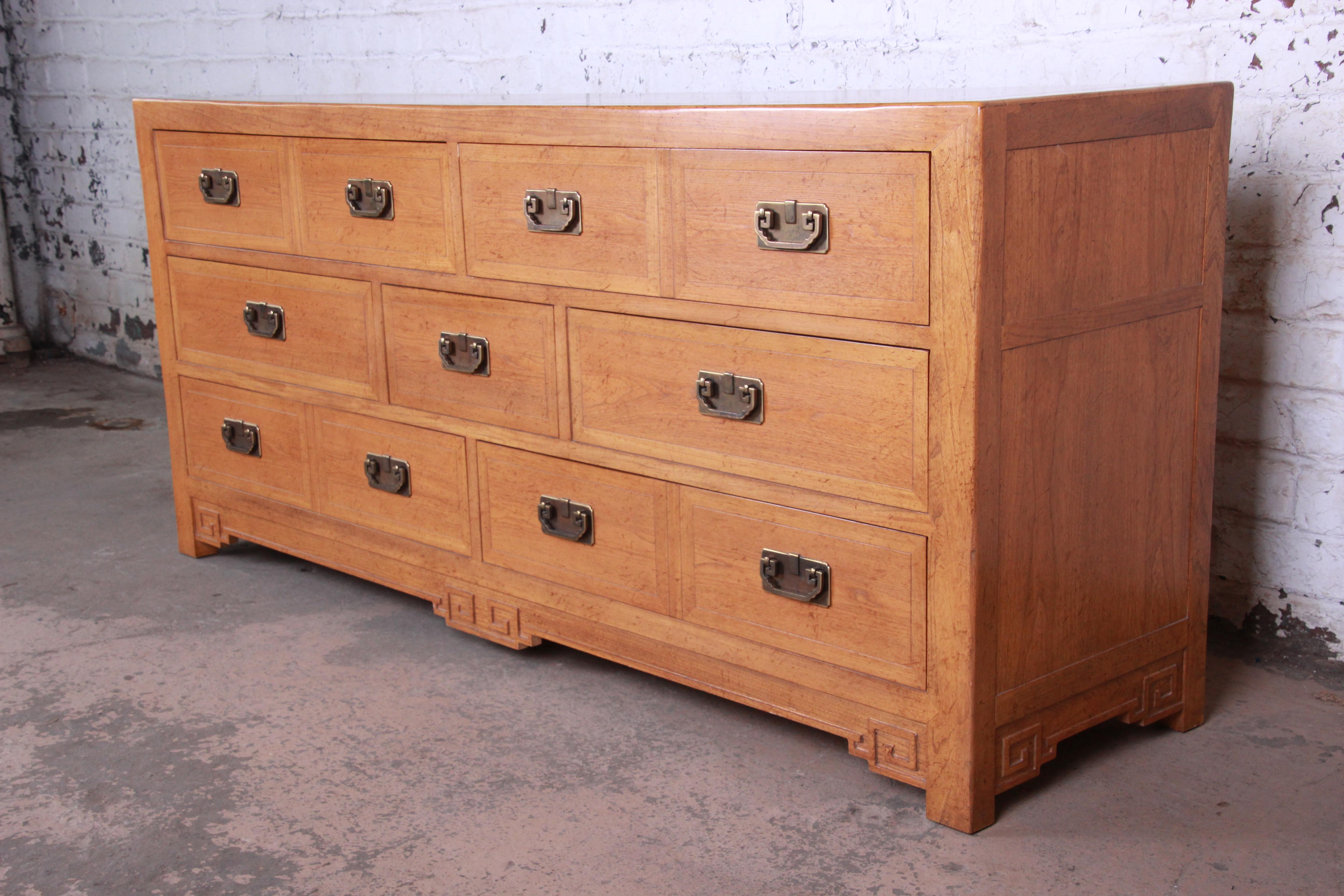 A very nice elm wood chinoiserie long dresser or credenza designed by Michael Taylor for his Far East collection for Baker Furniture. The dresser has beautiful Asian-inspired brass hardware and carved wood details. It offers ample room for storage,