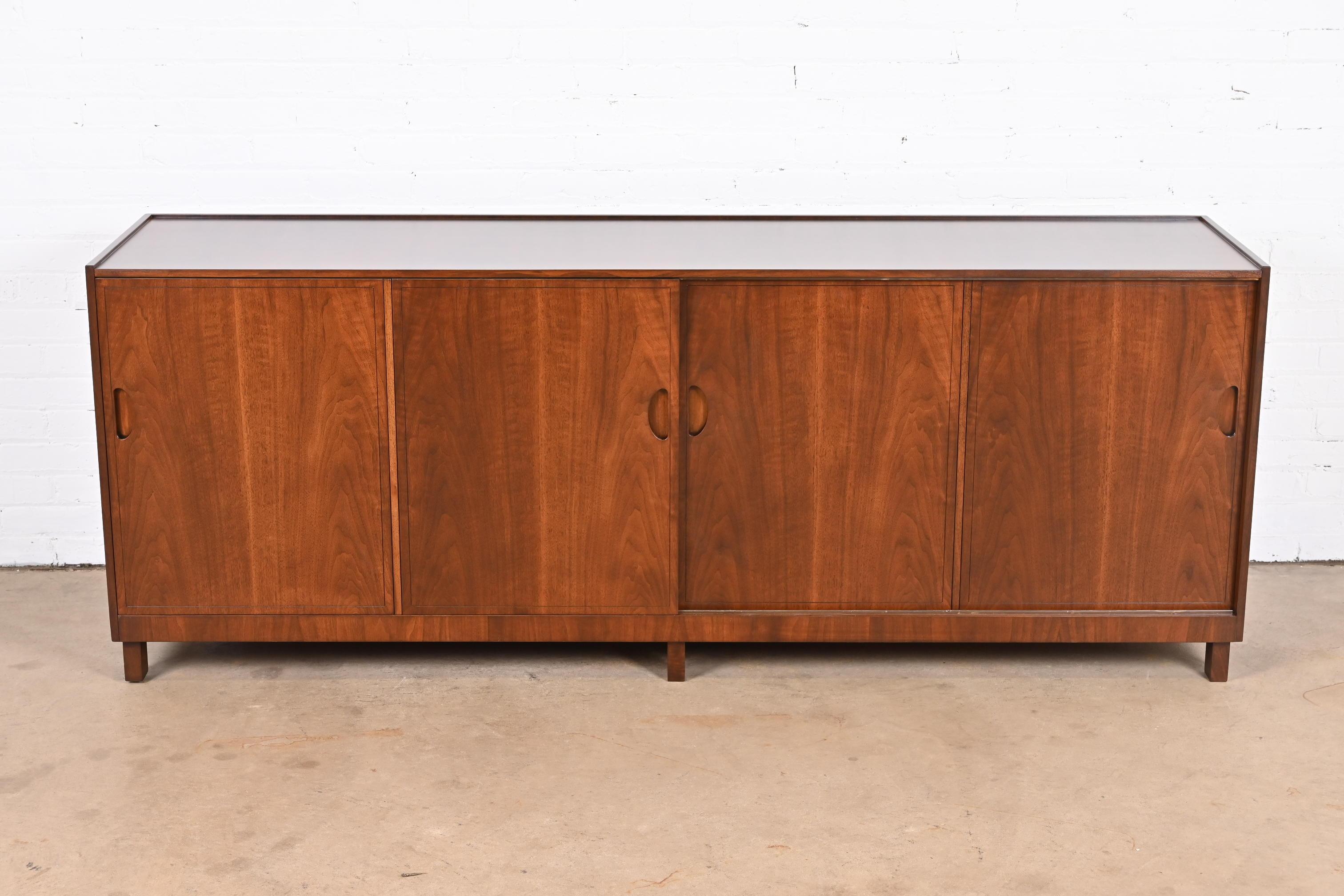 An exceptional Mid-Century Modern sideboard, credenza, or bar cabinet

by Michael Taylor for Baker Furniture.

USA, 1960s

Stunning book-matched walnut, with recessed handles, sliding doors, and felt-lined silverware insert in top