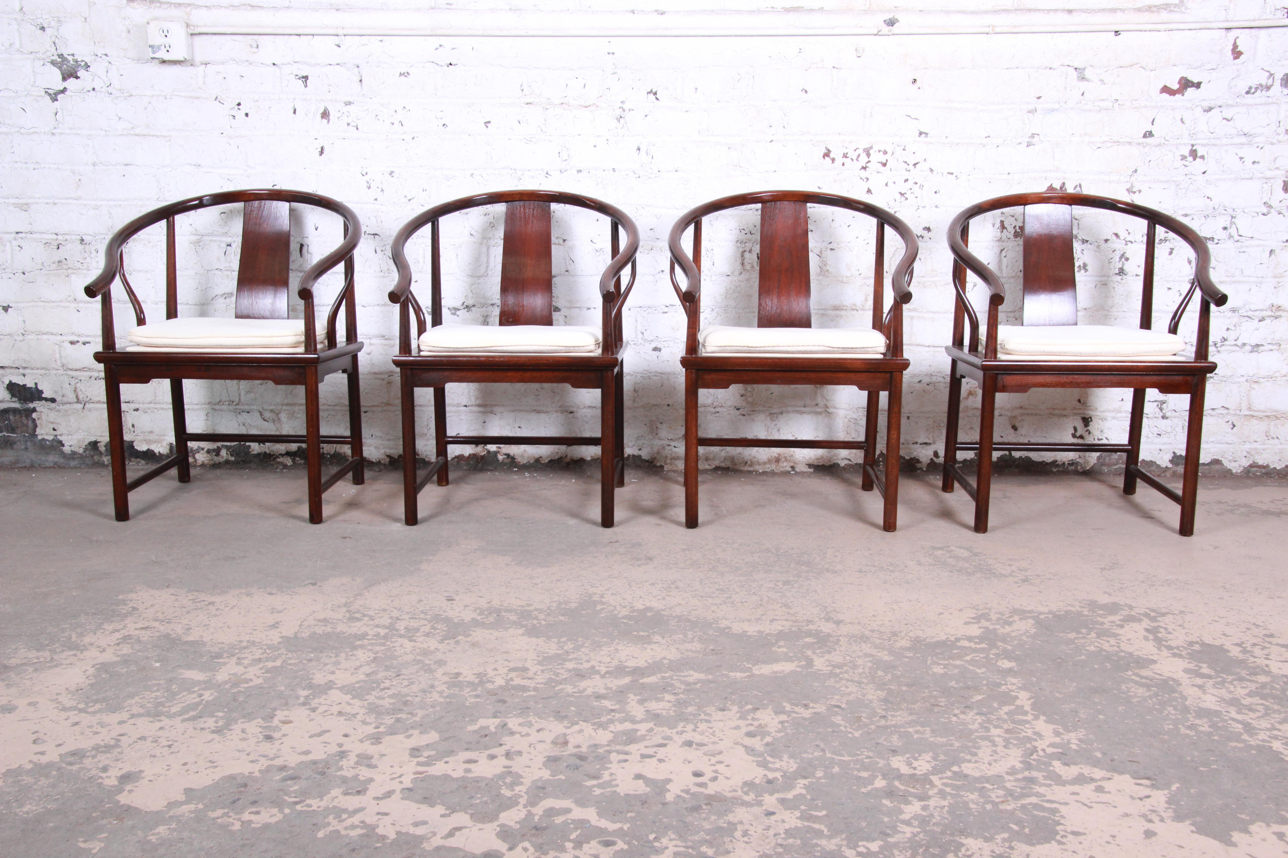 An exceptional set of four Hollywood Regency chinoiserie armchairs designed by Michael Taylor for his Far East collection for Baker Furniture. The chairs feature solid walnut frames with an Asian-inspired horseshoe design. The ivory upholstery with