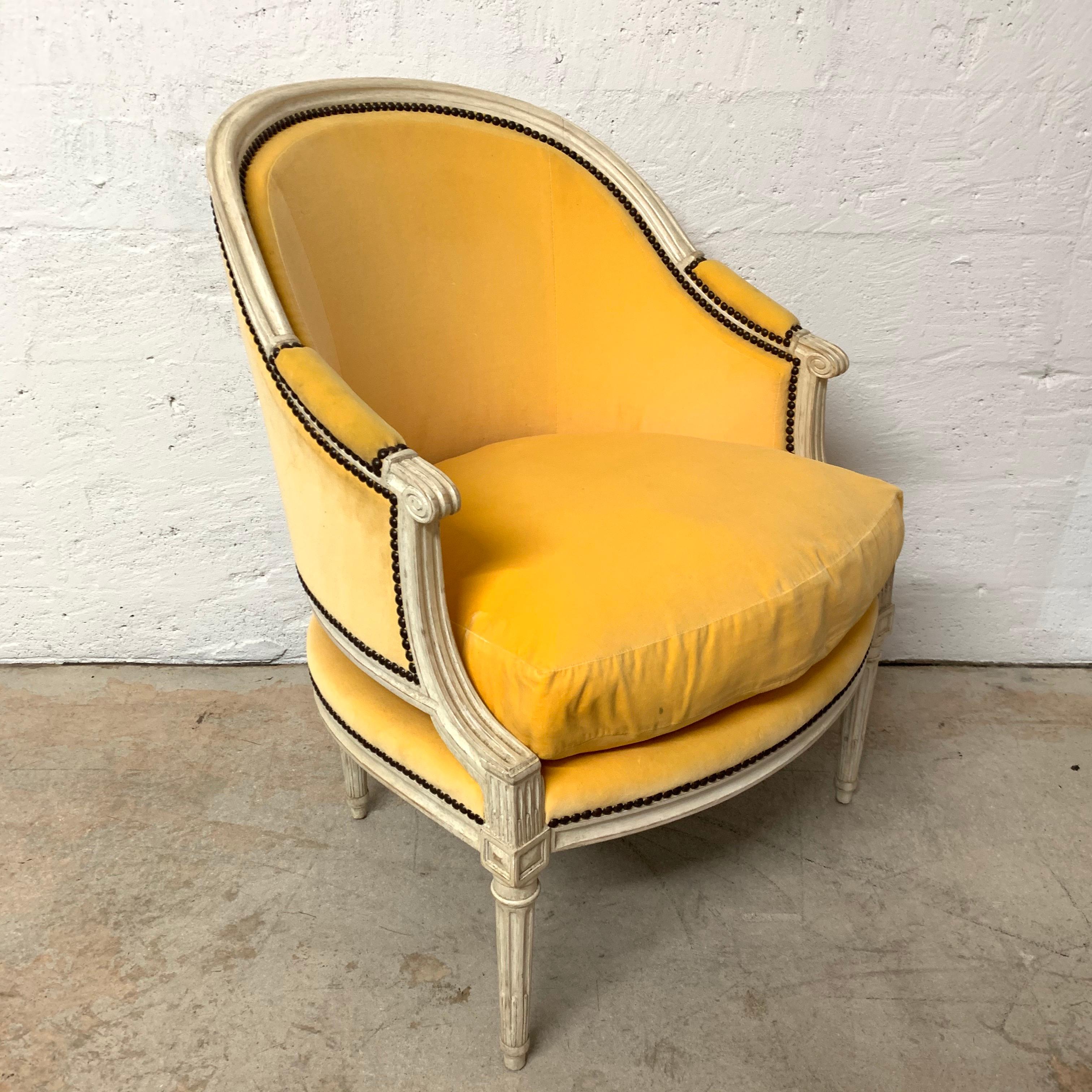 Louis XV style bergère chair rendered in antique white painted wood frame with canary yellow velvet upholstery and nailheads, designed and manufactured by Michael Taylor Designs.