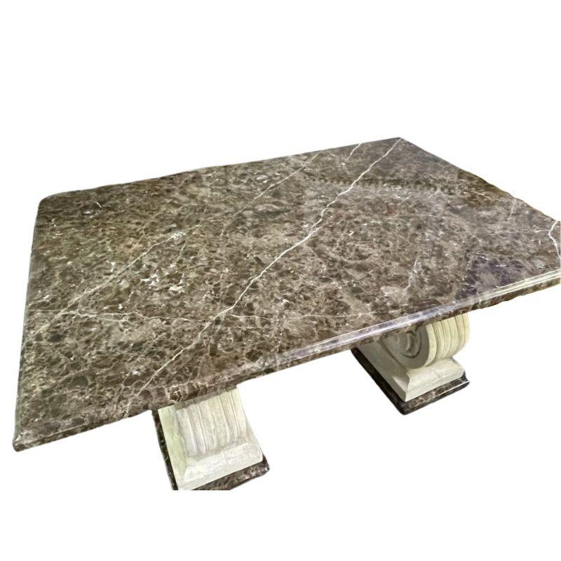 A Michael Taylor marble top and double pedestal stone base dining table for use indoors or outdoors.  The marble top shows beautiful shades of brown and white veins run through it.  The stone double pedestal base are ornately carved in  symmetrical