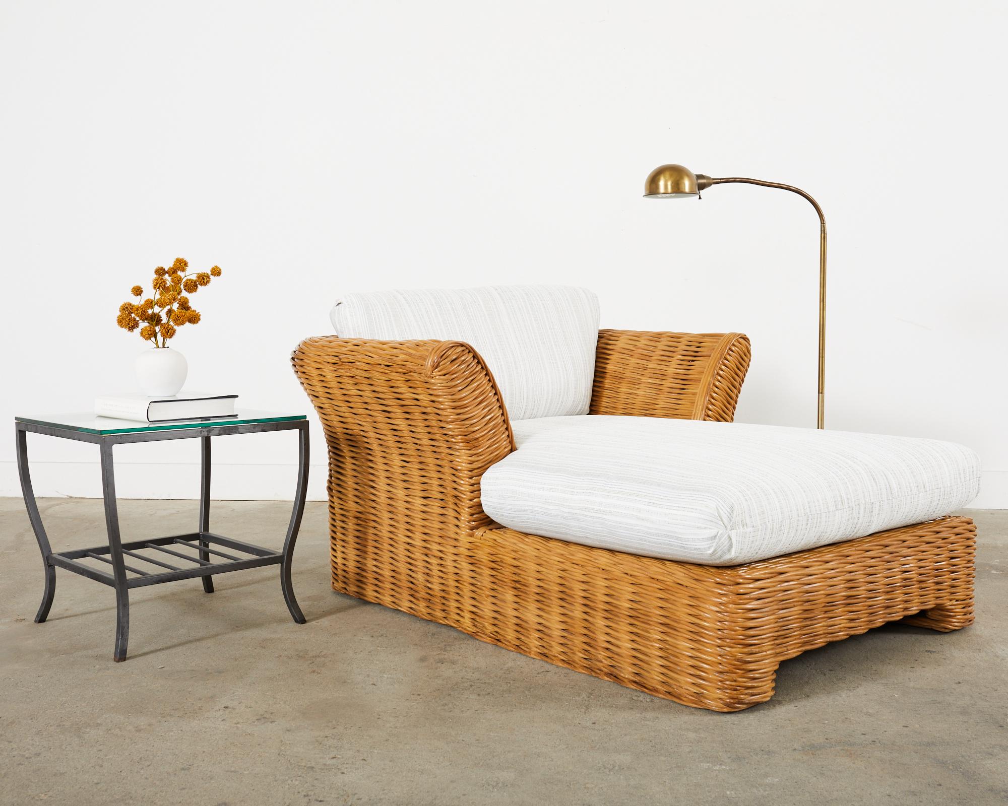 Grand organic modern chaise longue or chaise lounge chair crafted from thick pencil reed woven rattan in the California coastal manner and style of Michael Taylor. The chaise features a large frame with dramatic flared arms on each side. The frame