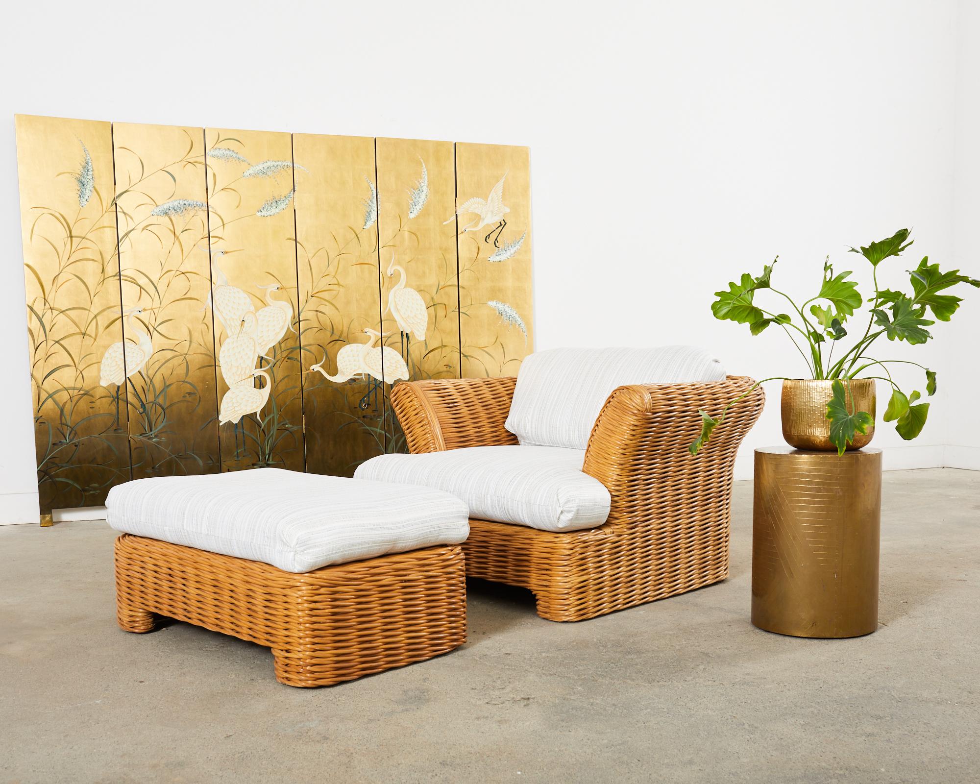 Oversized organic modern lounge chair and ottoman crafted from thick pencil reed woven rattan in the California coastal style and manner of Michael Taylor. The chair features a large frame with dramatic flared arms. Newly upholstered fabric on the