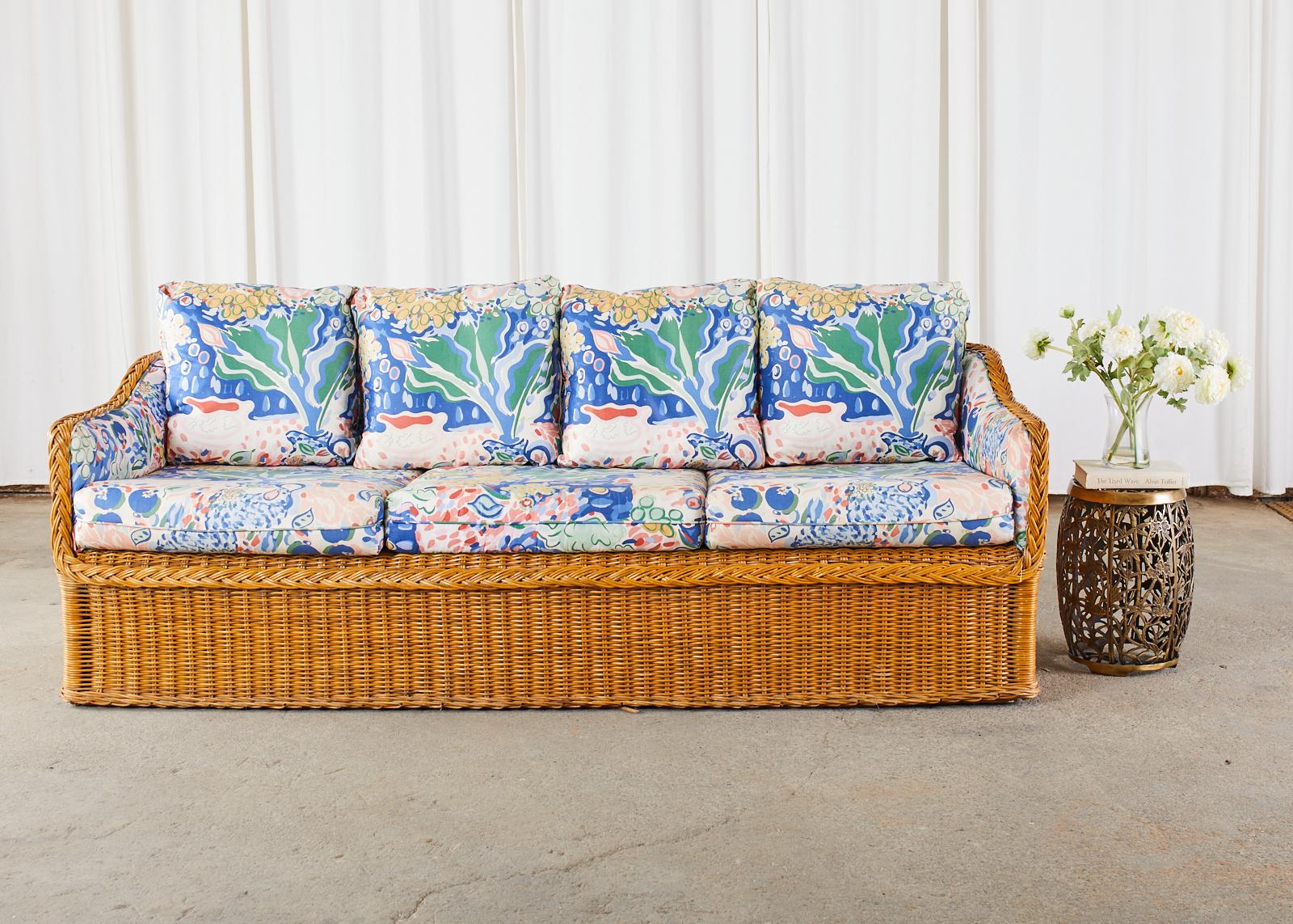 Stylish organic modern sofa made in the manner and style of Michael Taylor. The large 3 seat sofa features a rattan frame covered with woven wicker having a braided border. Upholstered with a colorful vintage fabric in a floral motif. The three seat