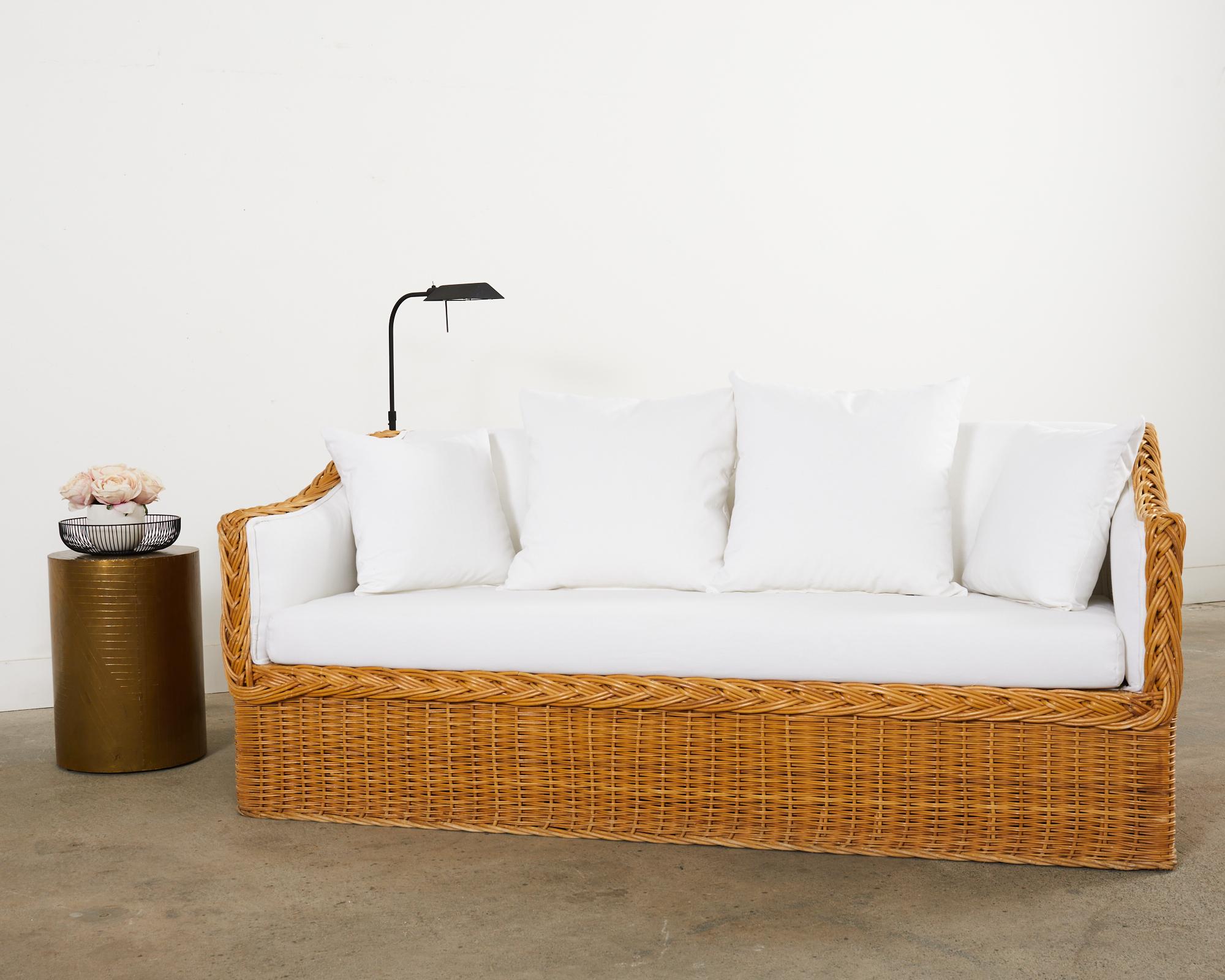 Gorgeous wicker rattan sofa settee made in the California coastal organic modern style and manner of Michael Taylor. Attributed to Wicker Works in San Francisco the sofa features a wood frame covered with woven wicker having a braided rattan border.