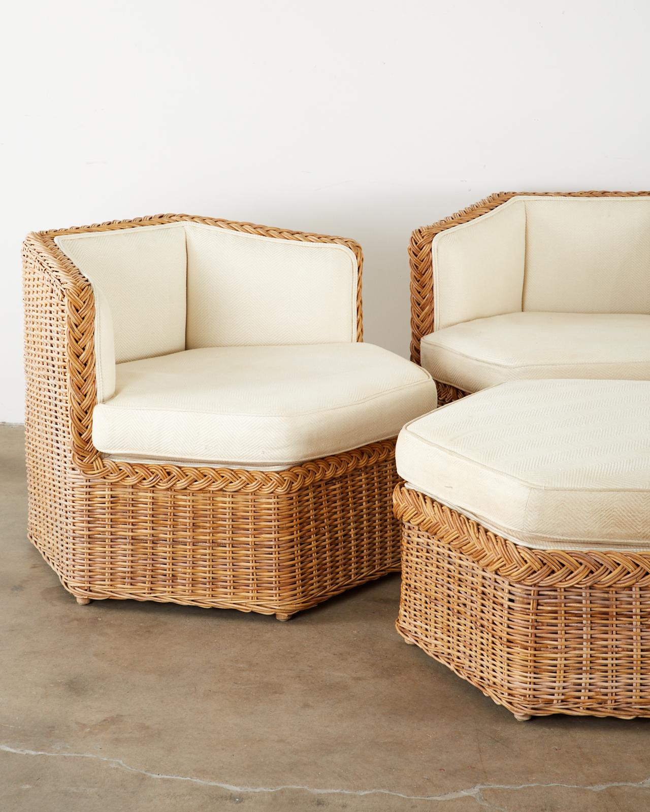 Stylish modular seating sofa set or suite consisting of three hexagonal shaped lounge chairs and a conforming ottoman. Handcrafted from woven rattan wicker in the manner and style of Michael Taylor. Topped with off-white thick cushions and padded