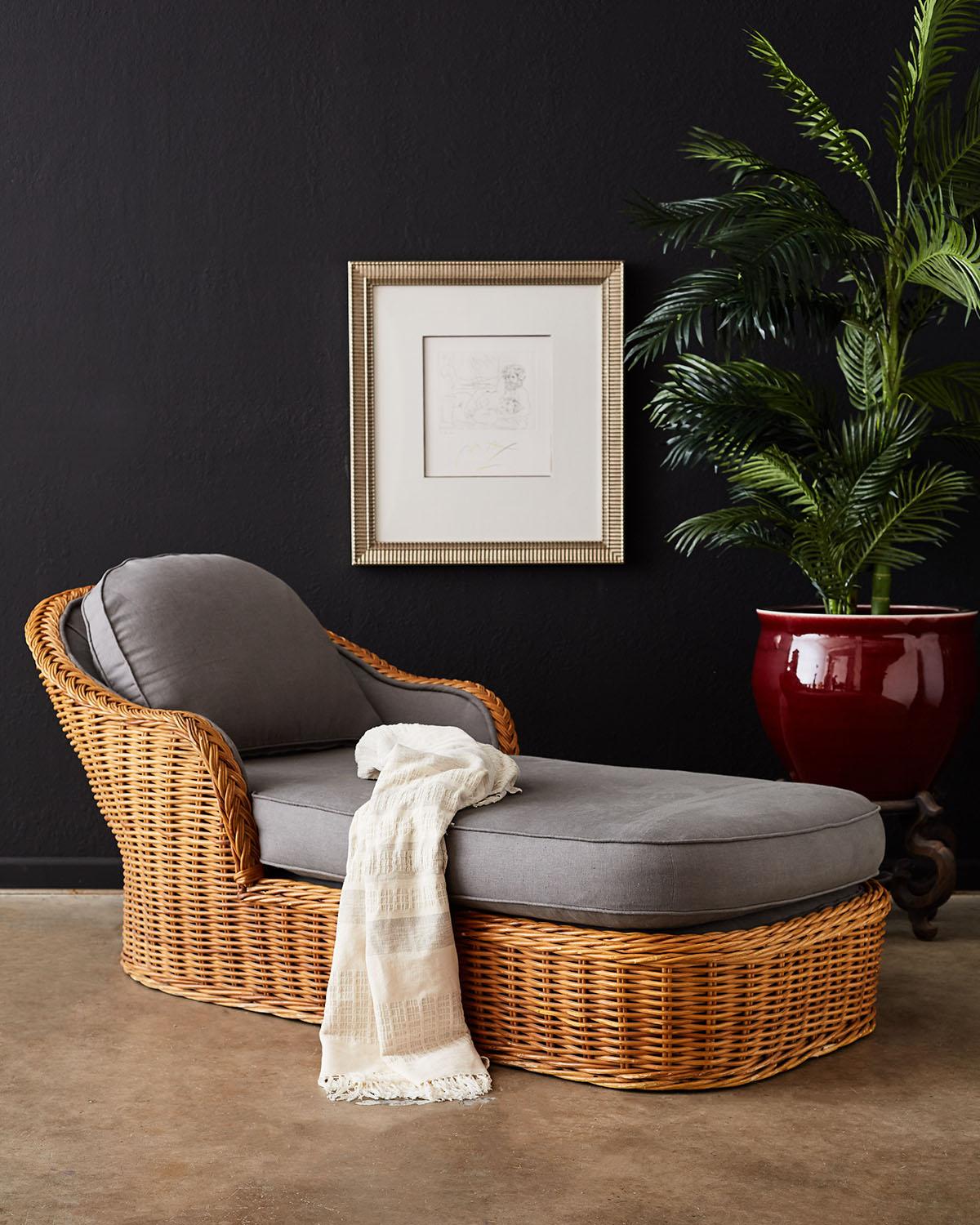 Oversized wicker and rattan chaise lounge or chaise longue made in the manner and style of Michael Taylor. Large rattan frame covered with woven stick wicker with a decorative braided arm crest. The generous seat has a thick cushion on top and a