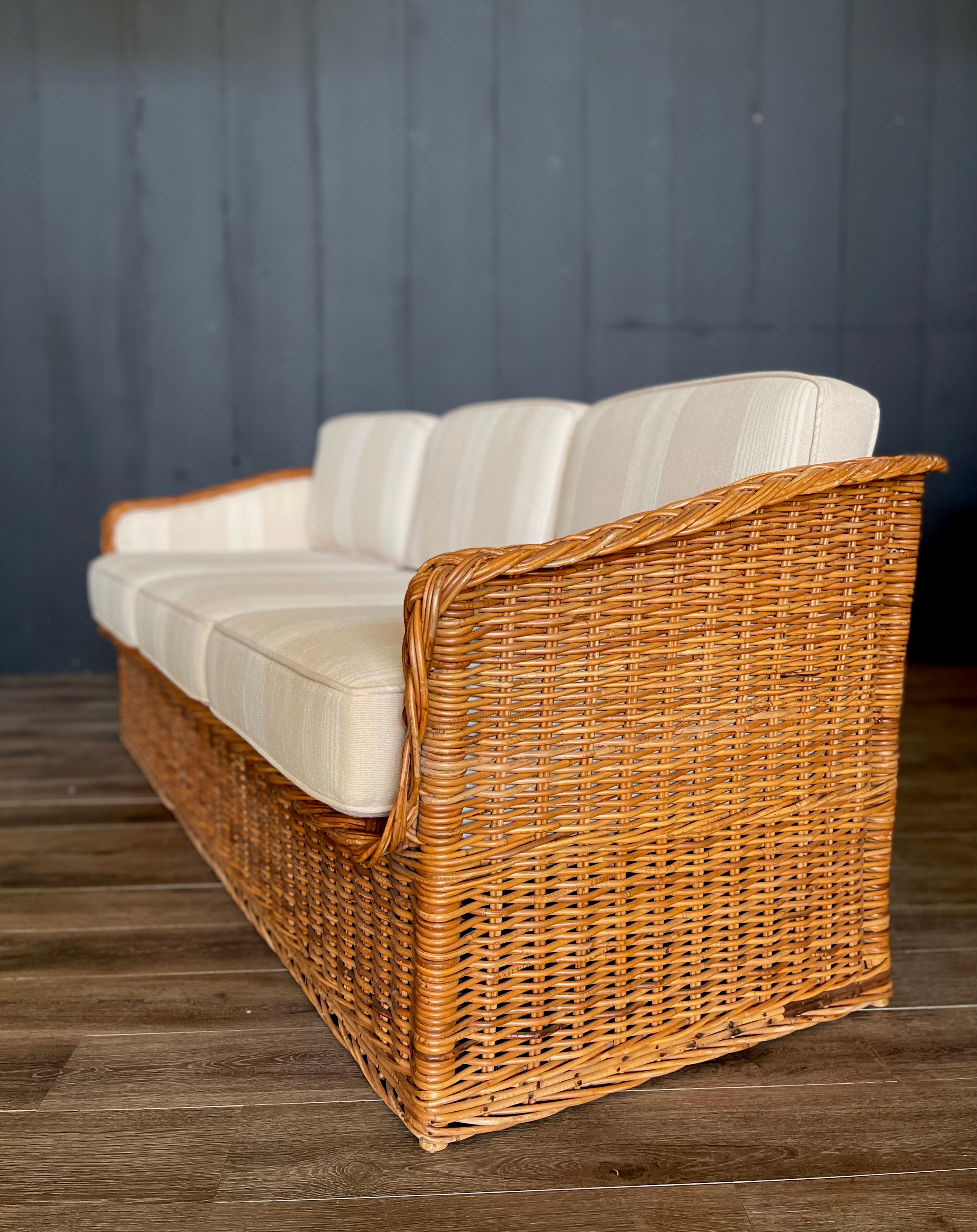 Add a touch of classic design to your retreat, whether by the water or in the mountains, with this stunning Michael Taylor style mid-century wicker rattan sofa, meticulously reupholstered in high-performance neutral striped fabric for durability and