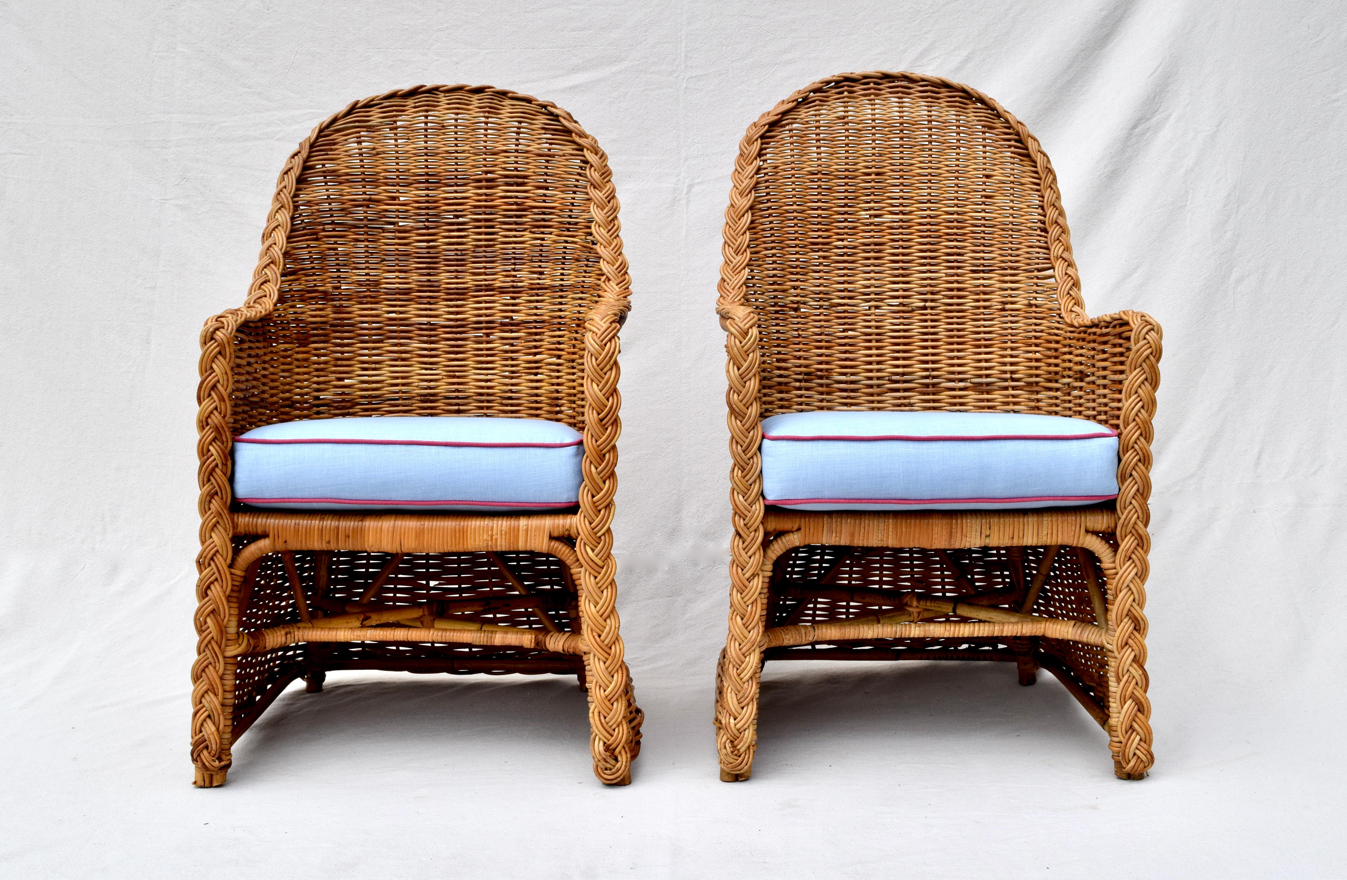 A pair of Michael Taylor braided wicker rattan armchairs with new loose cushions upholstered in new stock vintage Ralph Lauren sky blue and cranberry linen. Additionally each chair includes one goose down cushion upholstered in Brunschwig & Fils