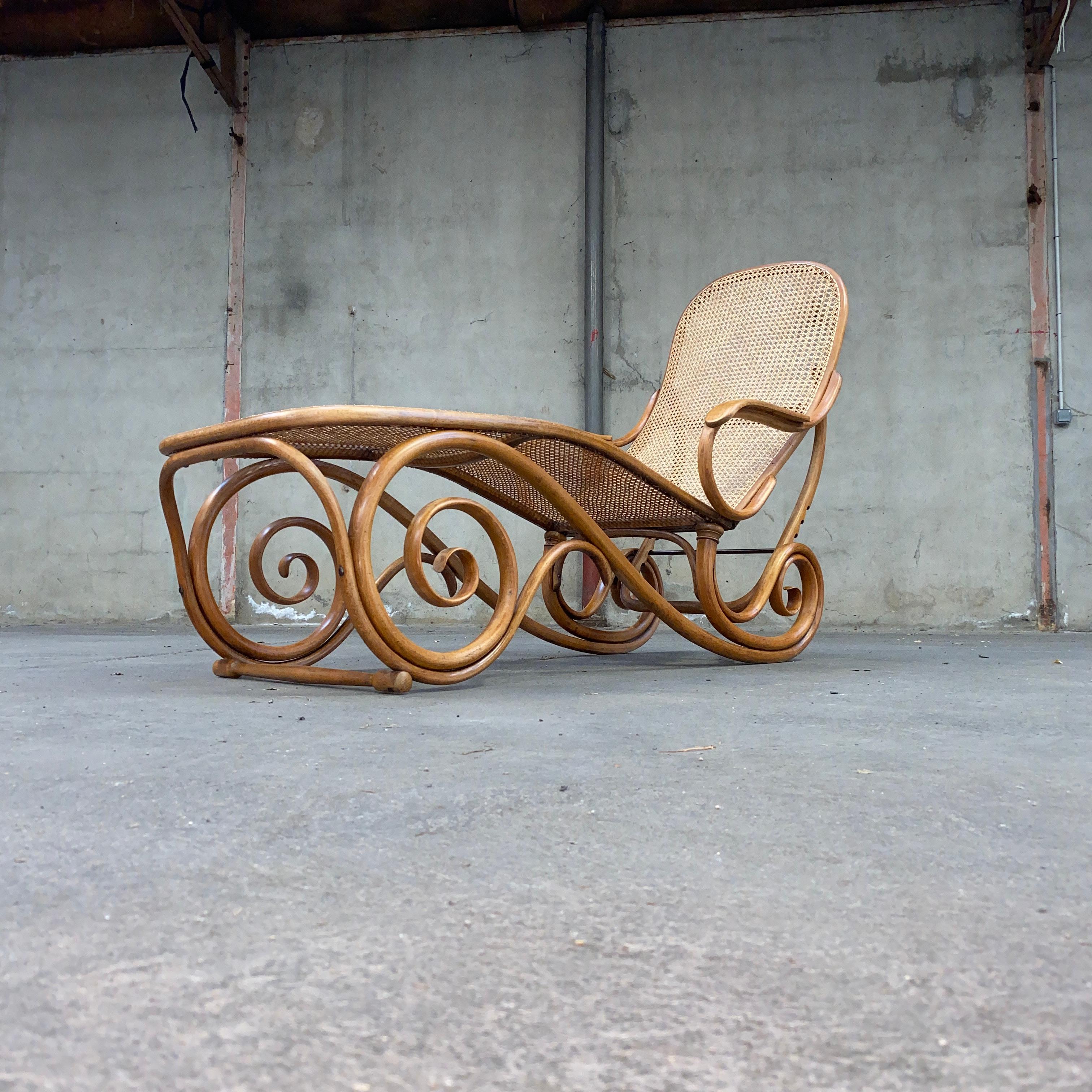 Michael Thonet, 
La chaise en bois courbé autrichienne est composée de hêtre avec un dossier réglable à deux accoudoirs, un piètement à volutes et une assise en panneaux de cannage.
Canne neuve et en parfait état.