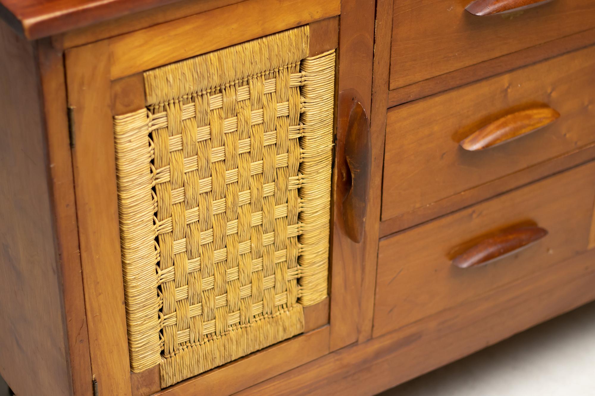 An important solid mahogany cupboard with doors on either side, 3 drawers at the centre and a display with sliding glass doors on top. The doors and sidewalls frame a beautiful basket weave of rattan cord. 

Provenance:
The office of the Mexican