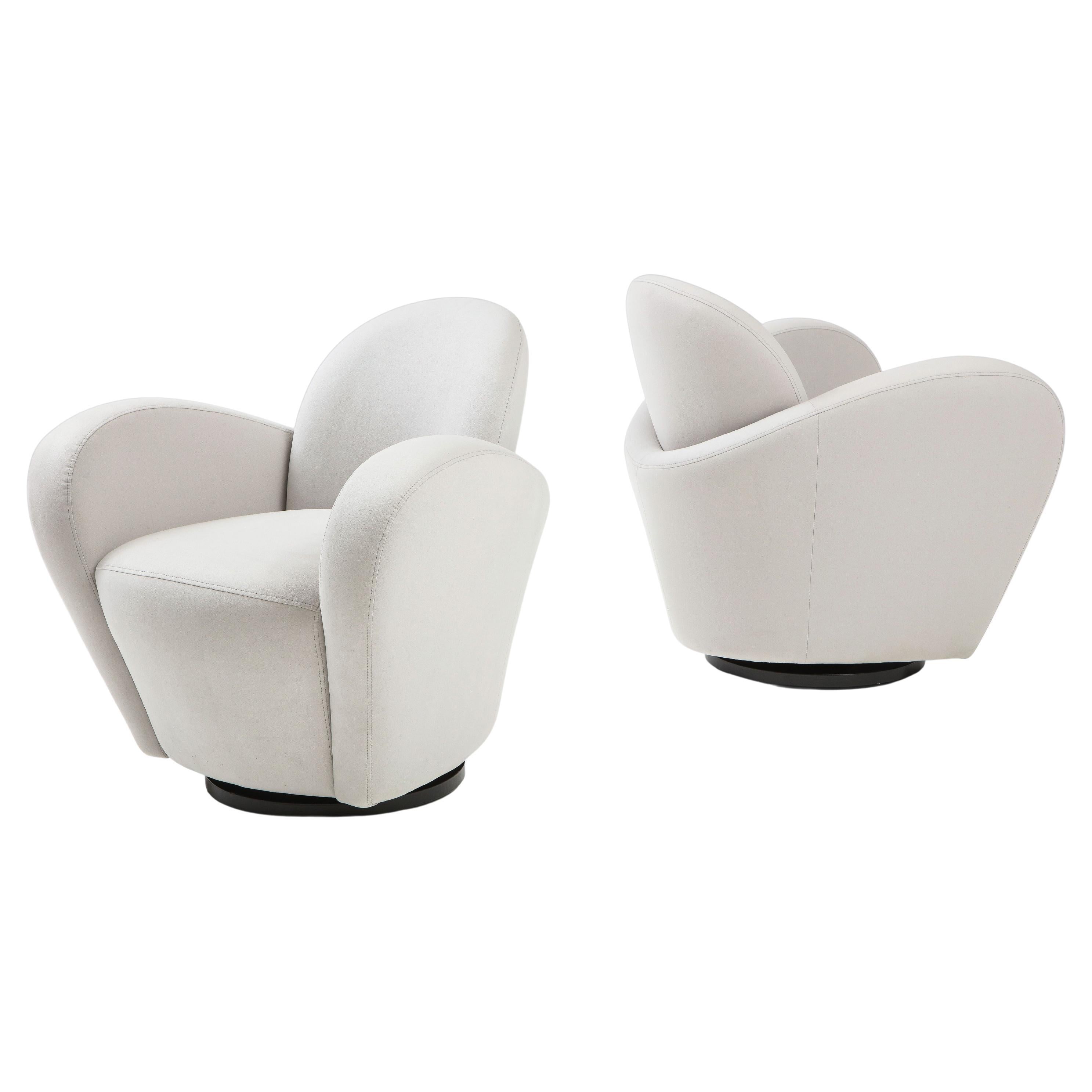 Michael Wolk for Directional pairs or set of four swivel lounge chairs in light gray Sensuede with elegantly curved wraparound arms which taper down towards the bottom and resting on a black wooden swivel base. This iconic and chic design is playful