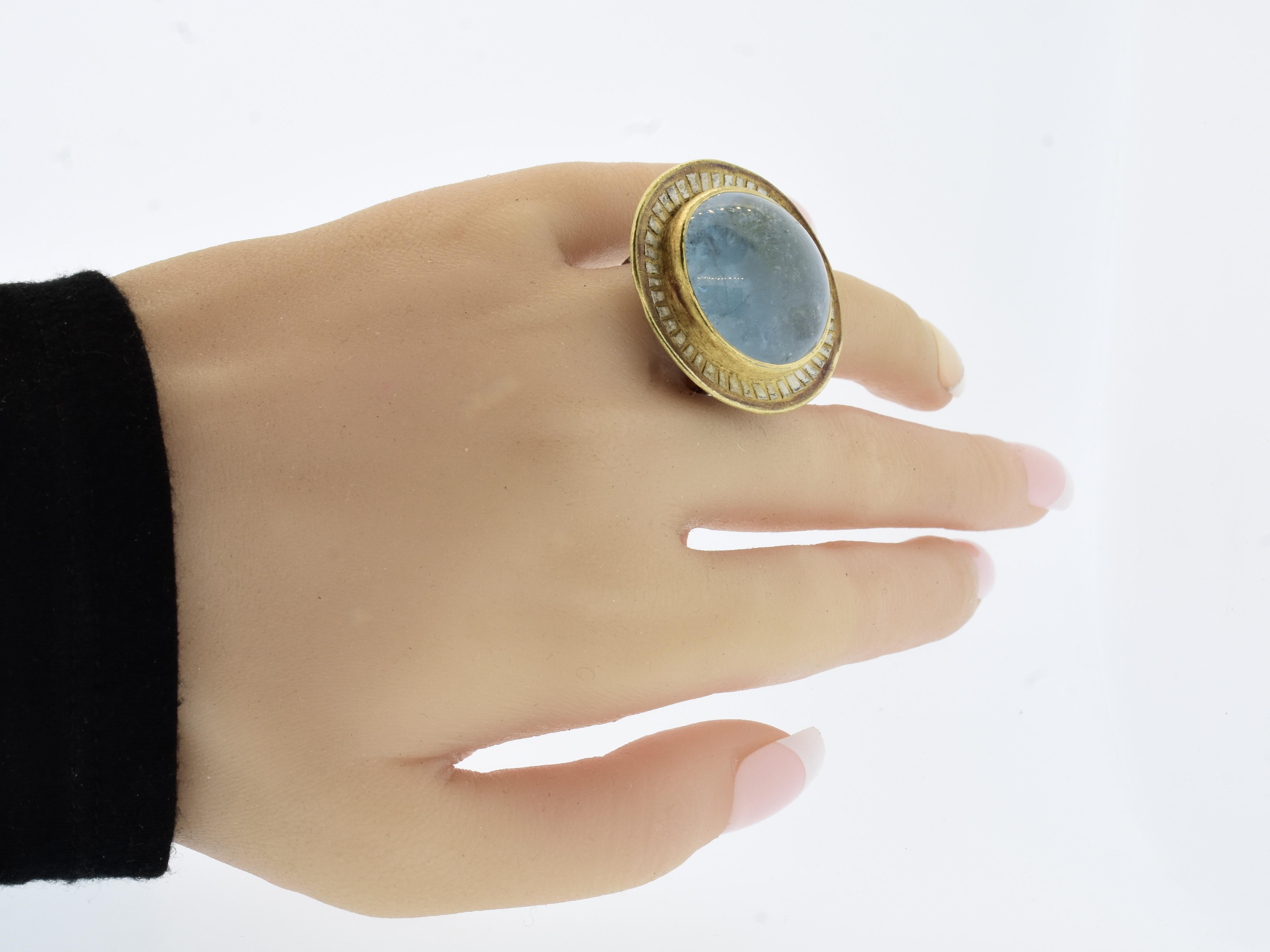 Contemporary jewelry artist Michael Zobel has hand crafted a highly unusual ring centering an approximately 47 ct. natural cabochon cut aquamarine bezel set in 22K yellow gold accented with stylized 'rays' of oxidized sterling silver on the gold top