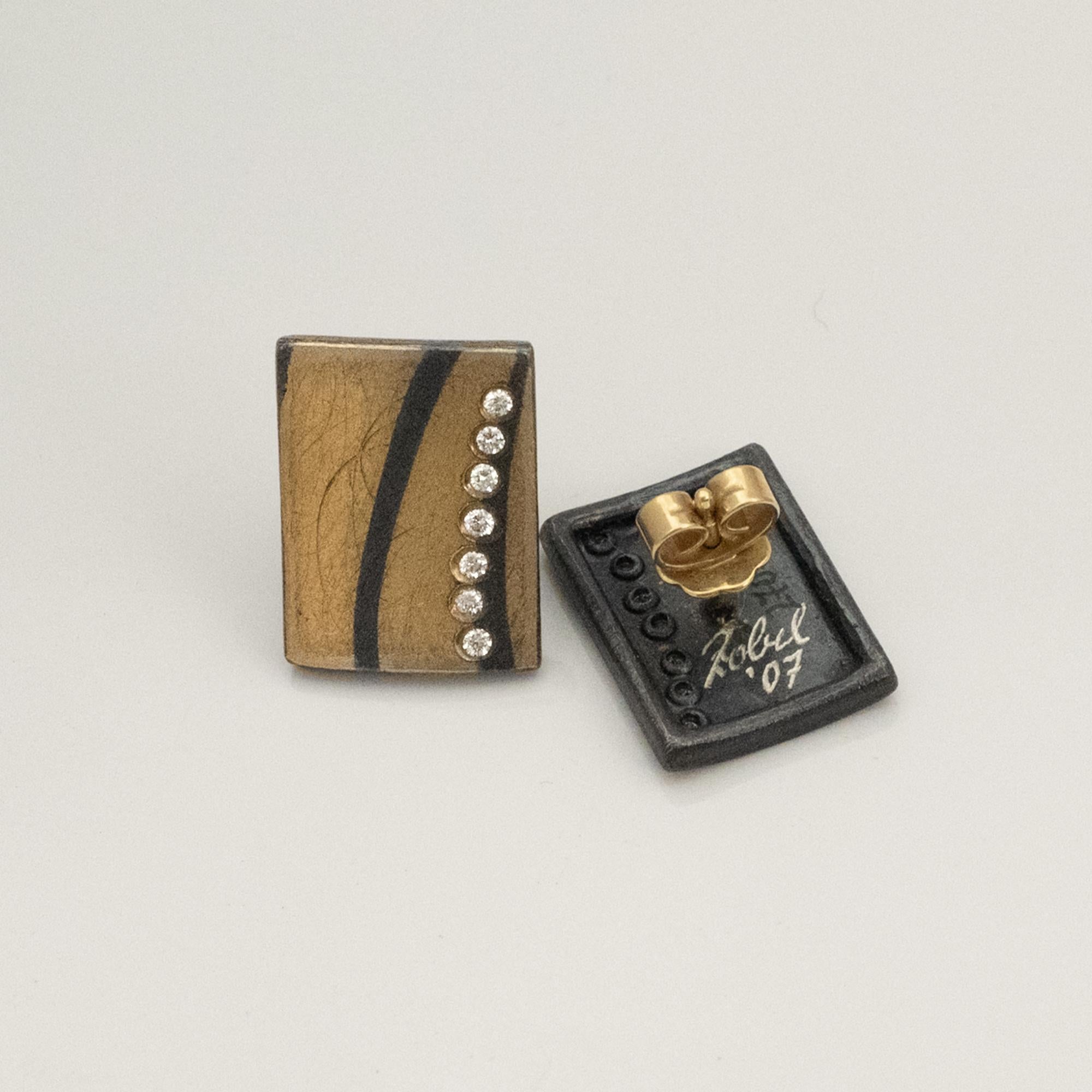 Questi orecchini rettangolari di Michael Zobel combinano l'oro e l'argento 18 carati opachi con accenti scuri a contrasto per creare una superficie grafica e audace. Una fila verticale di piccoli diamanti aggiunge una precisa linea di luminosità. Il