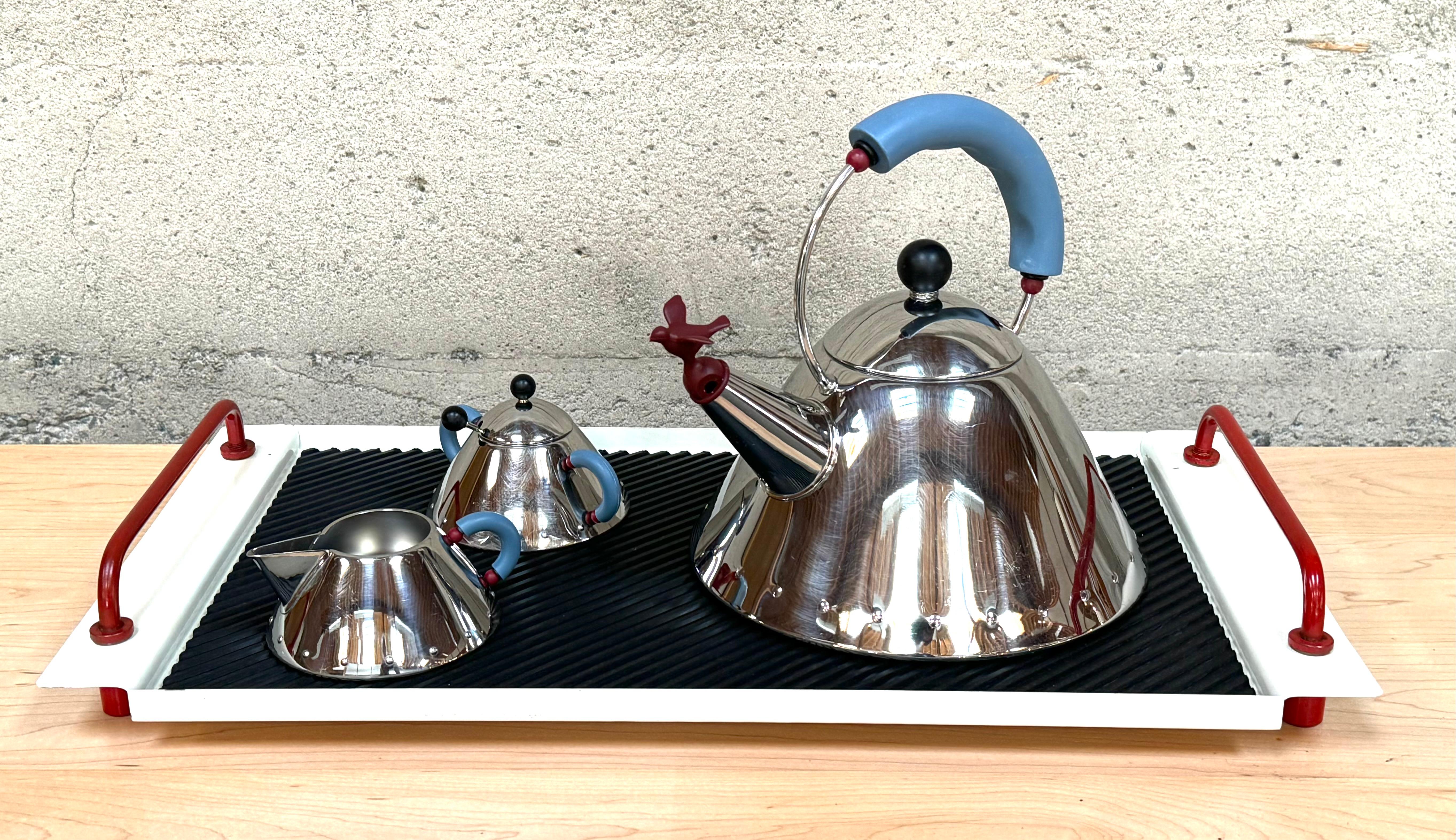 Micheal Graves for Alessi Tea Service circa 1980s Memphis Design example.
Stainless steel construction with colorful plastic accents for the handles and the bird whistle. The white and red tray with the black rubber mat is by Mas of Italy circa