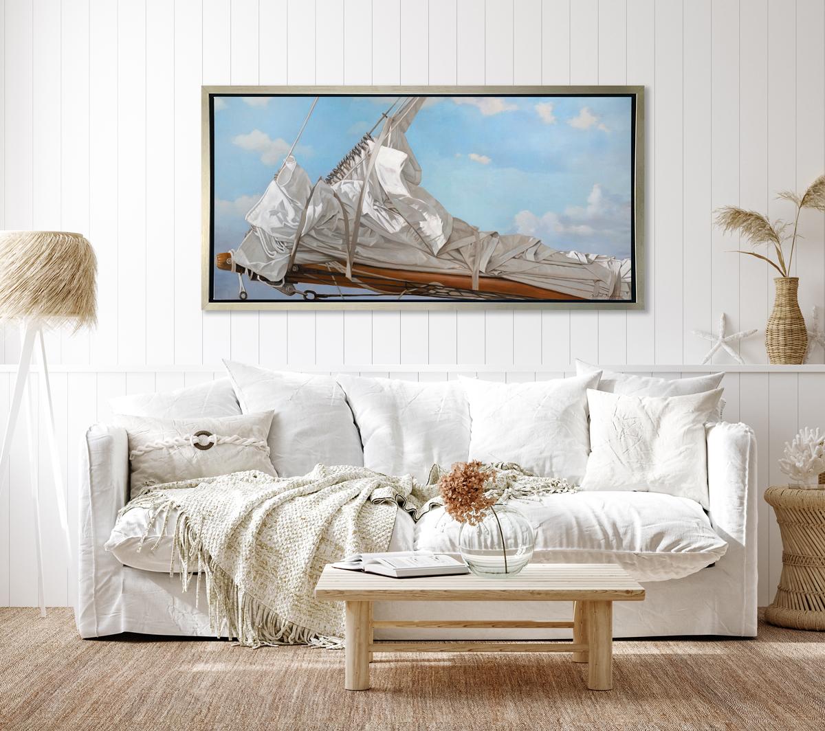 This realistic nautical limited edition print by Michel Brosseau captures the bow of a ship, with the sail tied down and a lightly cloudy blue sky behind it. The artist pays hyper attention to the folds and wrinkles of the sail fabric, creating a