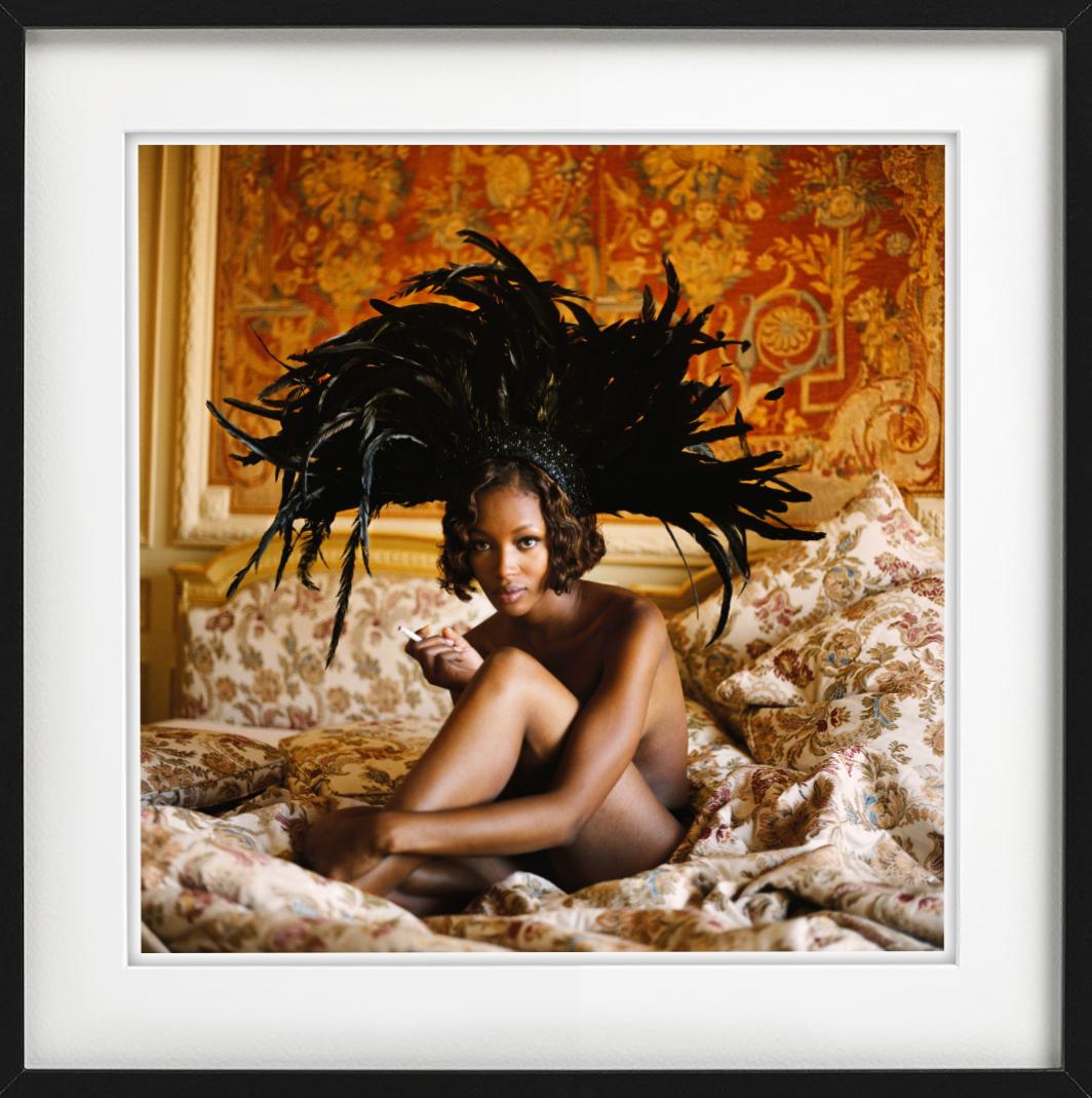 The Nude Supermodel sitting on a baroque bed in a black feather headpiece and smoking a cigarette, photographed by Michel Comte for Vogue Italia in 1993.

All prints are limited edition. Available in multiple sizes. High-end framing on request.

All